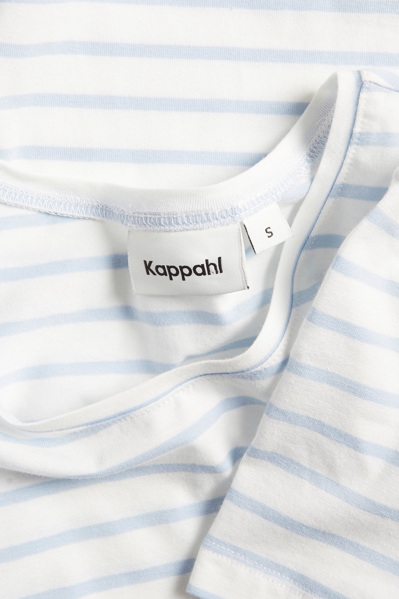 Nærbilde av en offwhite og lyseblå stripete kortermet basetopp med rund hals.