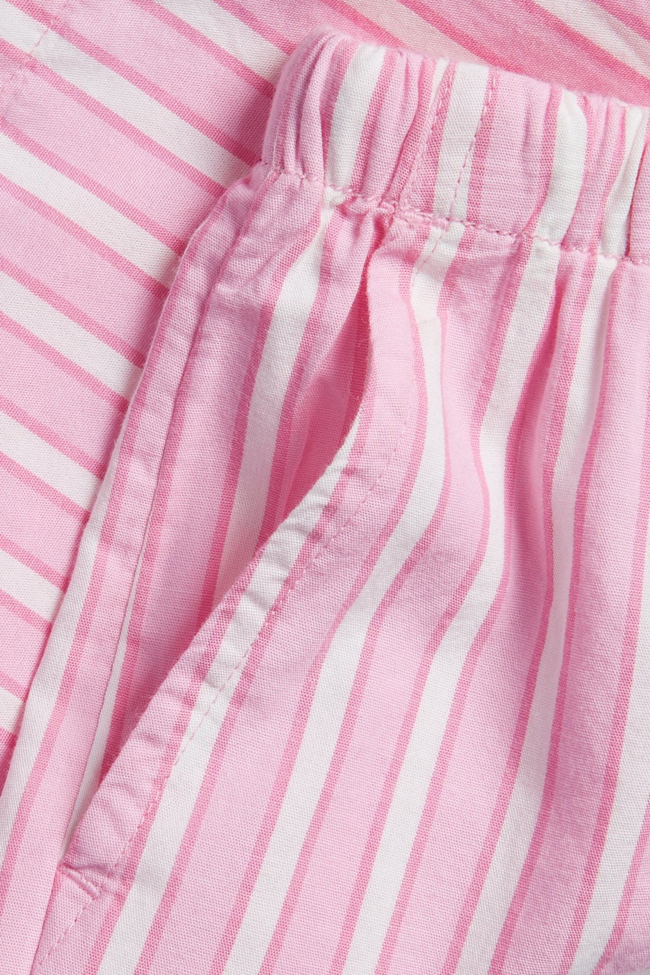 Zbliżenie różowo-białych bawełnianych szortów w paski z elastyczną talią i kieszeniami.