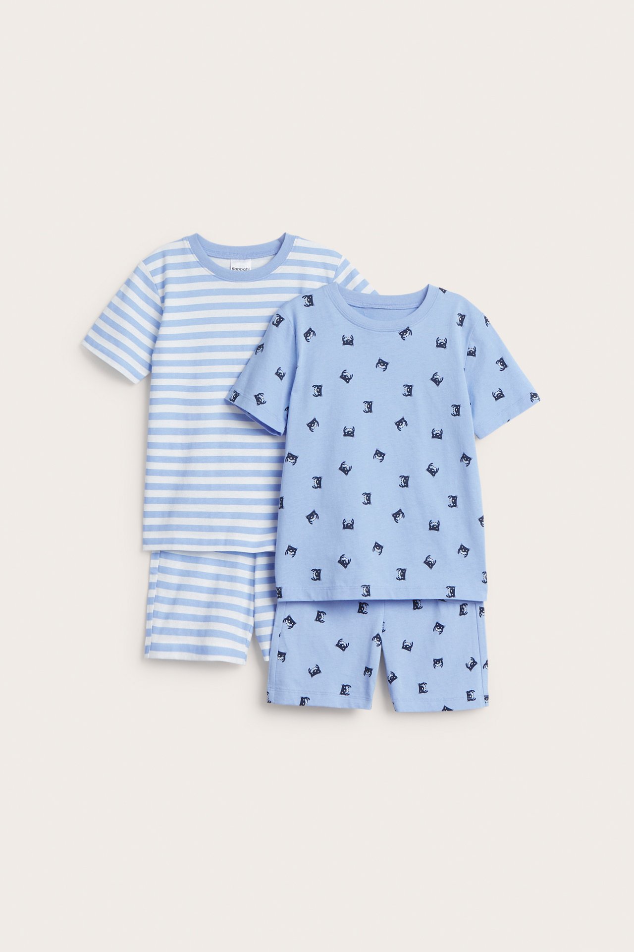 Edestä näkymä kahdesta lasten puuvillapyjamasta: toinen vaaleansininen rapukuvioilla, toinen raidallinen vaaleansinivalkoinen.