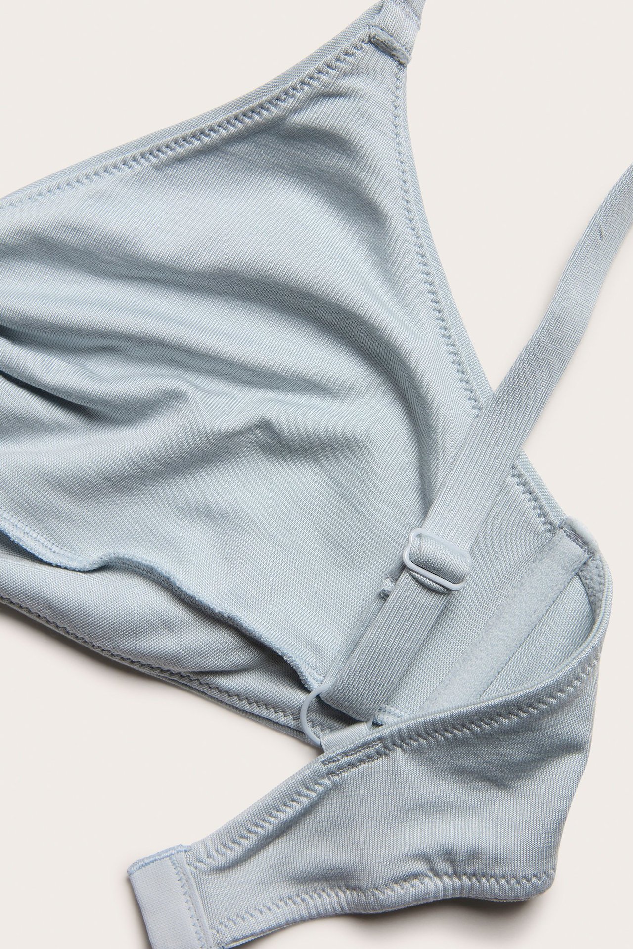 Zbliżenie na jasnoniebieski bralet z lyocellu z regulowanymi ramiączkami i węzłem z przodu.