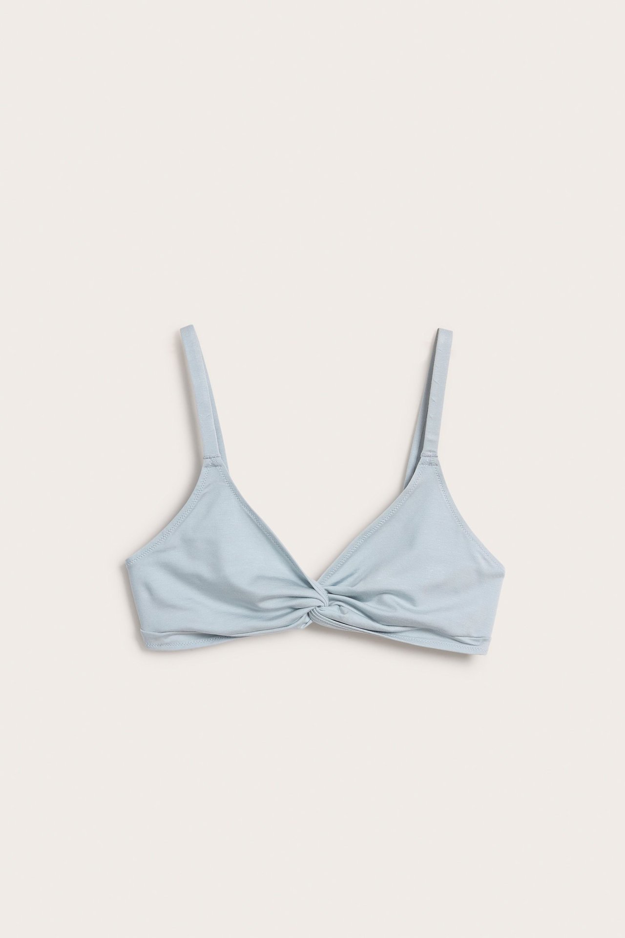 Framifrån, ljusblå lyocell bralette med knutdetalj fram och justerbara axelband.