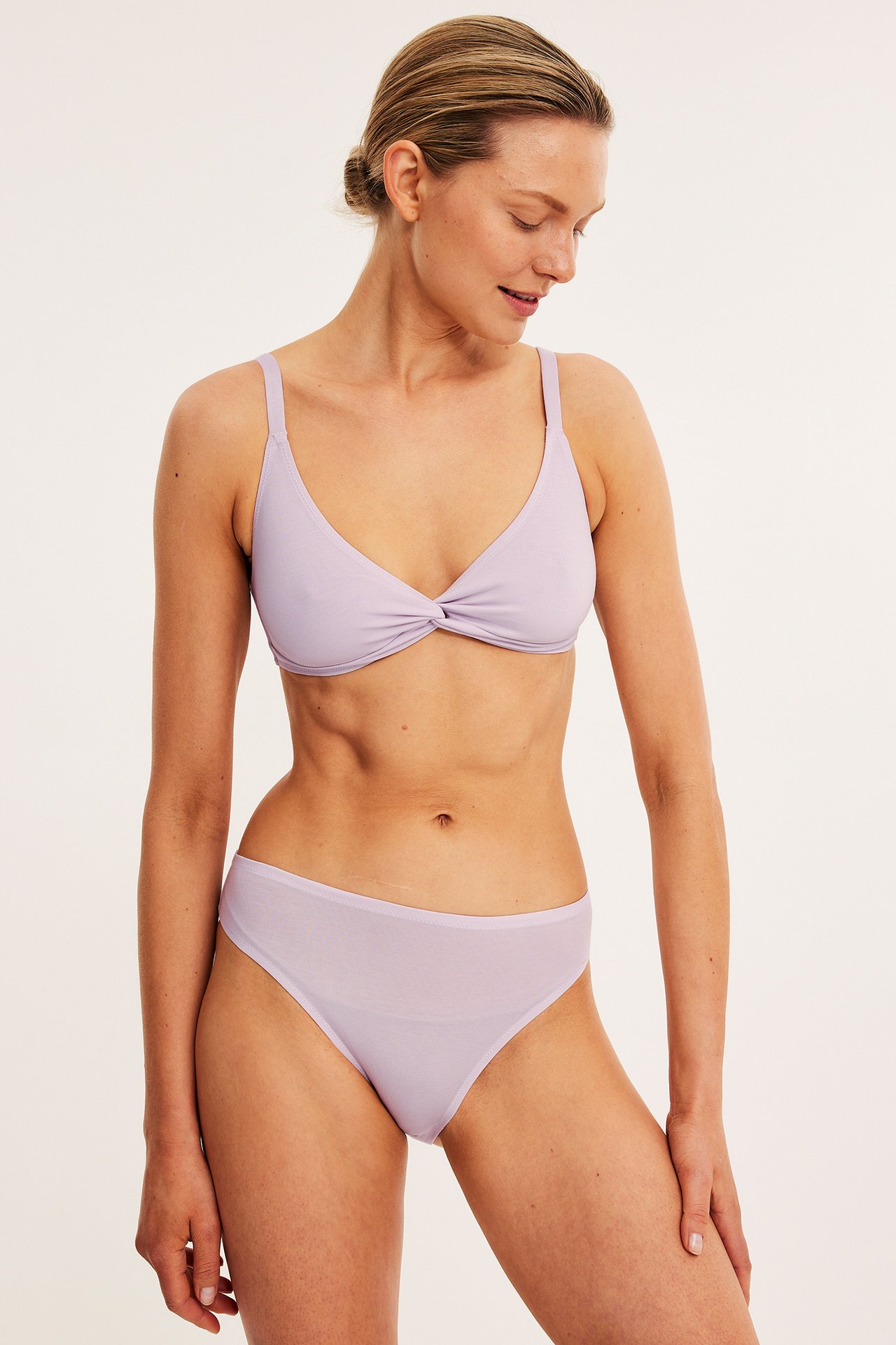 Framifrån, kvinna i ljusrosa lyocell bralette med knut fram och matchande trosor.