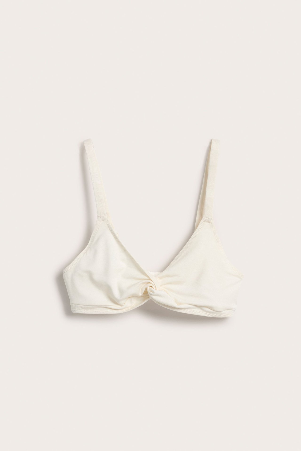 Framifrån, vit lyocell bralette med knutdetalj framtill och justerbara axelband.