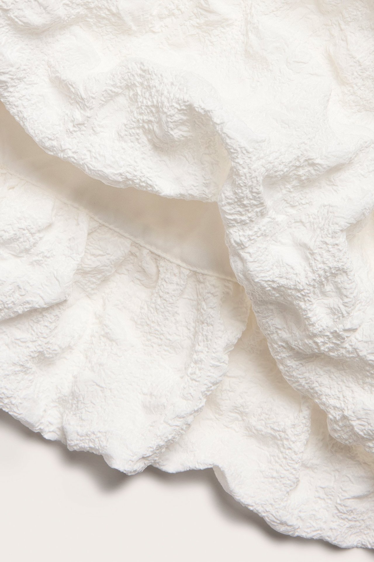 Närbild av en vit strukturerad ballongkjol i polyester.