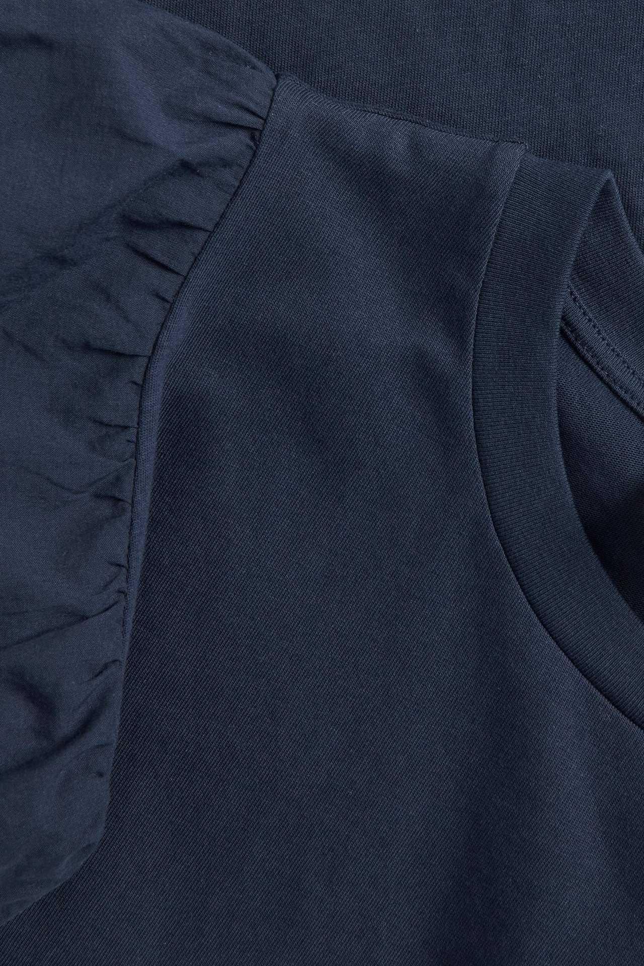 Zbliżenie na granatowy damski top z okrągłym dekoltem i bufiastymi rękawami.