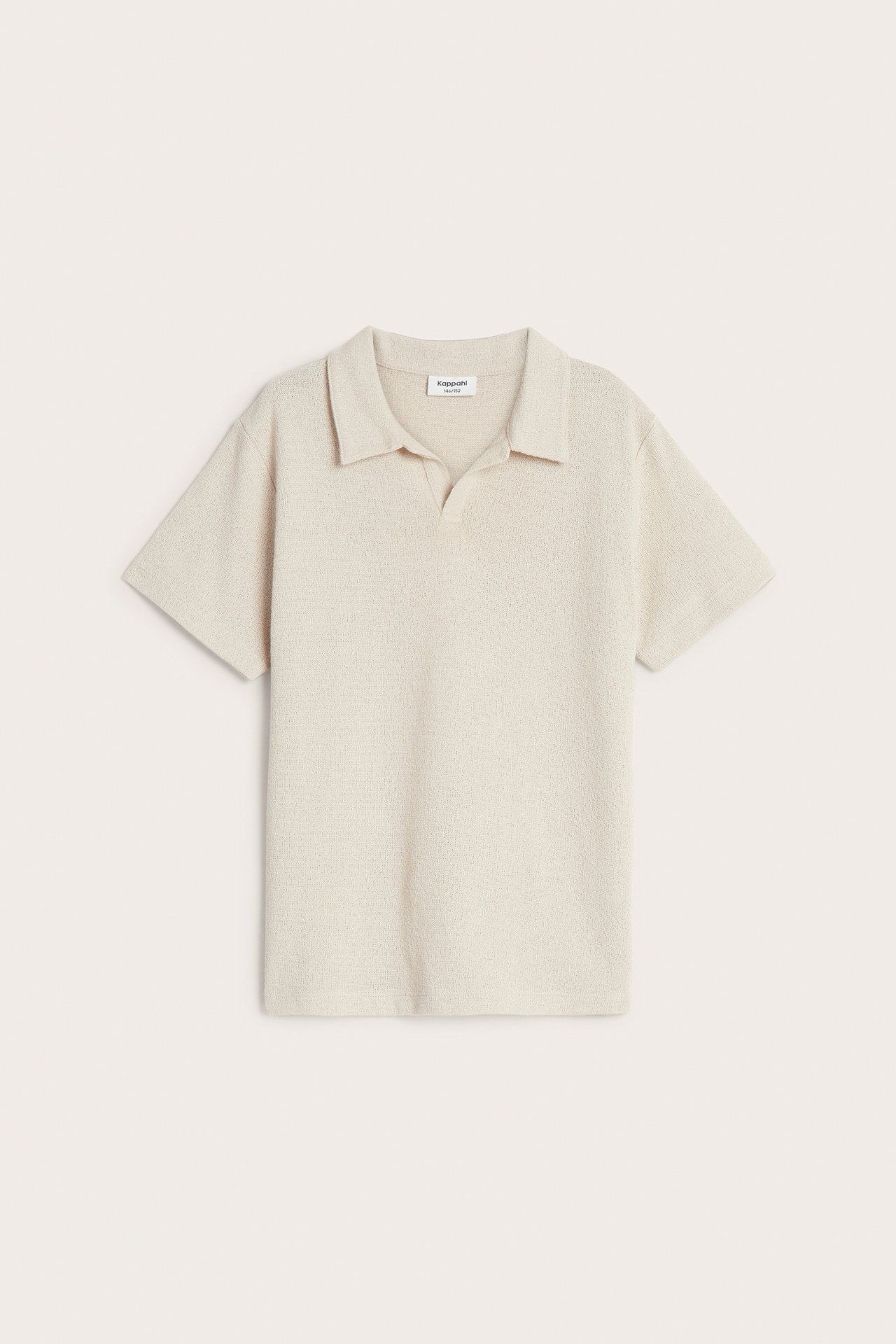 Edestäpäin, lasten beige hienoneulottu lyhythihainen pikeepaita klassisella kauluksella ja V-pääntiellä.