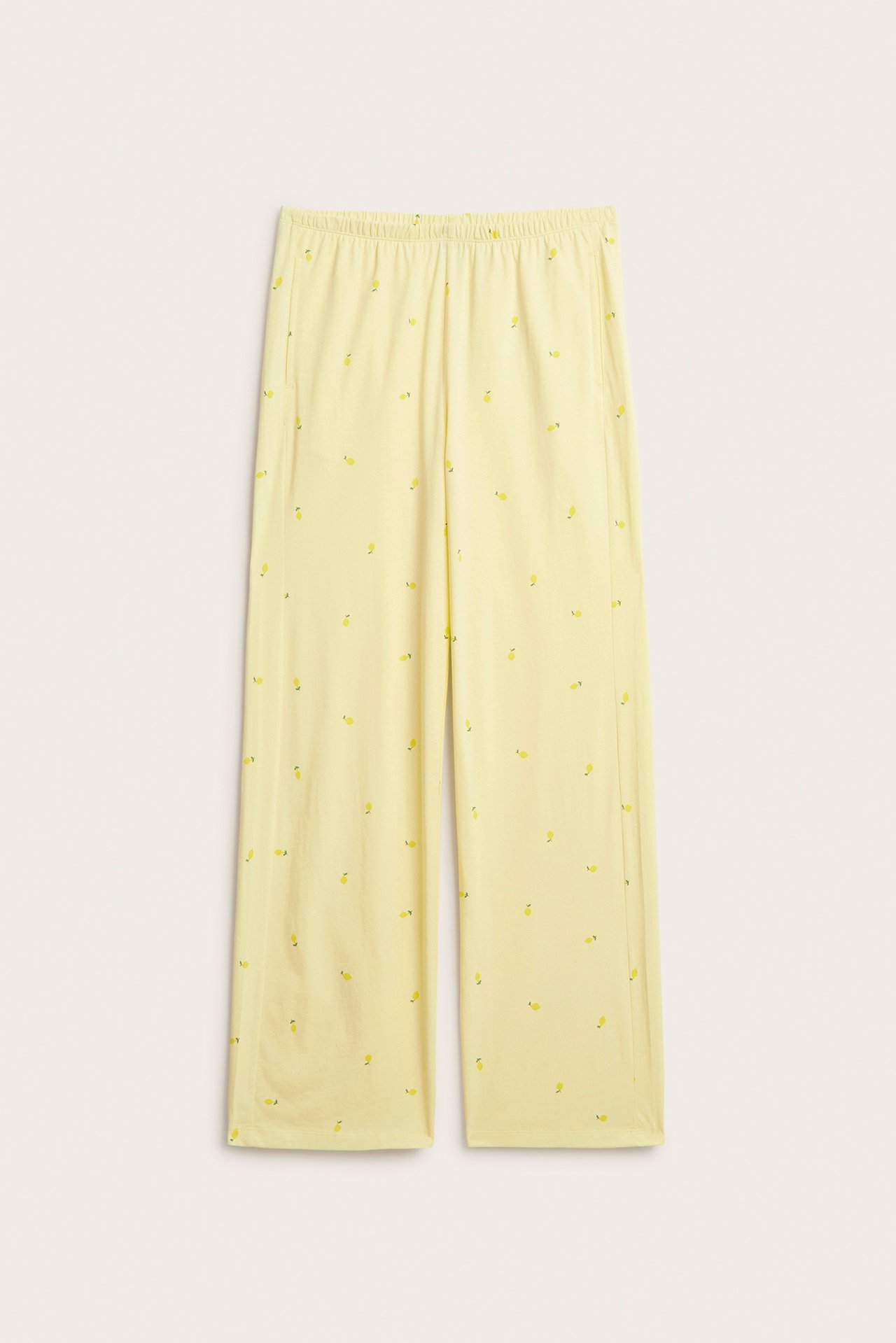 Frontvy: Ljusgula pyjamasbyxor i trikå med litet citronmönster, vida ben, resår i midjan, sidfickor.