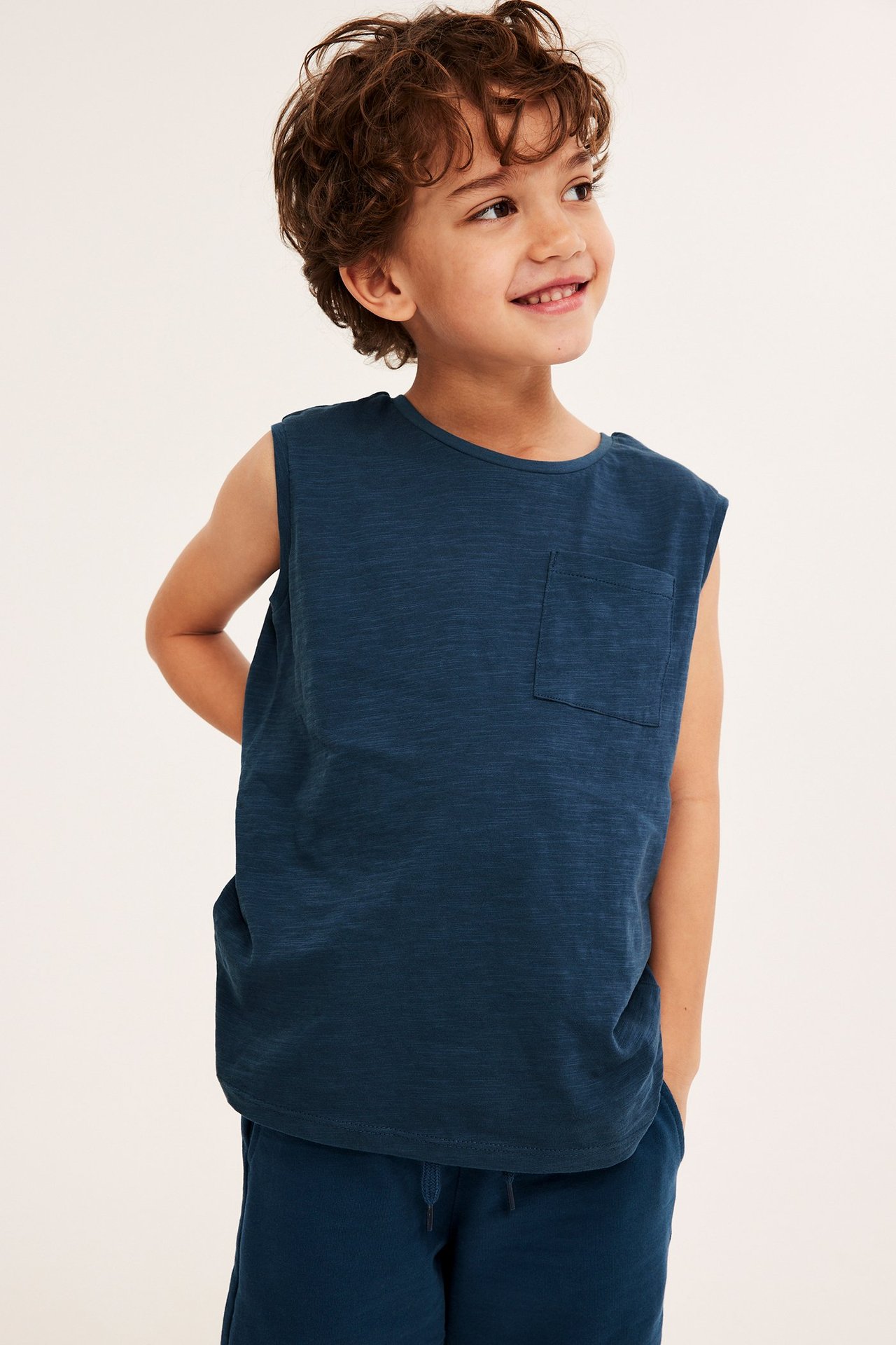 Widok z przodu: dziecko w granatowym bawełnianym podkoszulku z kieszonką na piersi i granatowych szortach.
