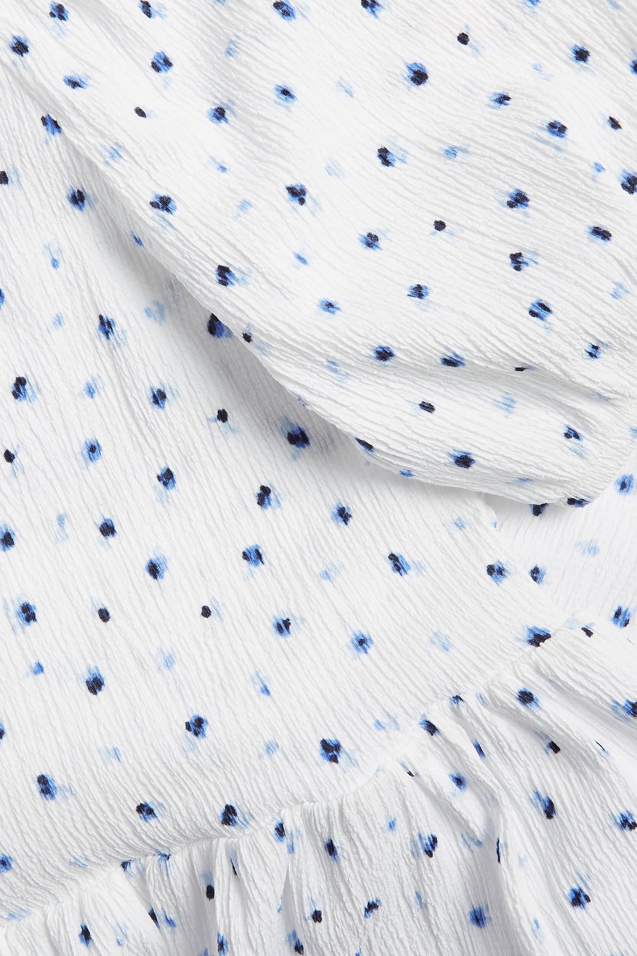 Zbliżenie białej sukienki z marszczonej dzianiny z niebieskim kwiatowym wzorem i falbanką.