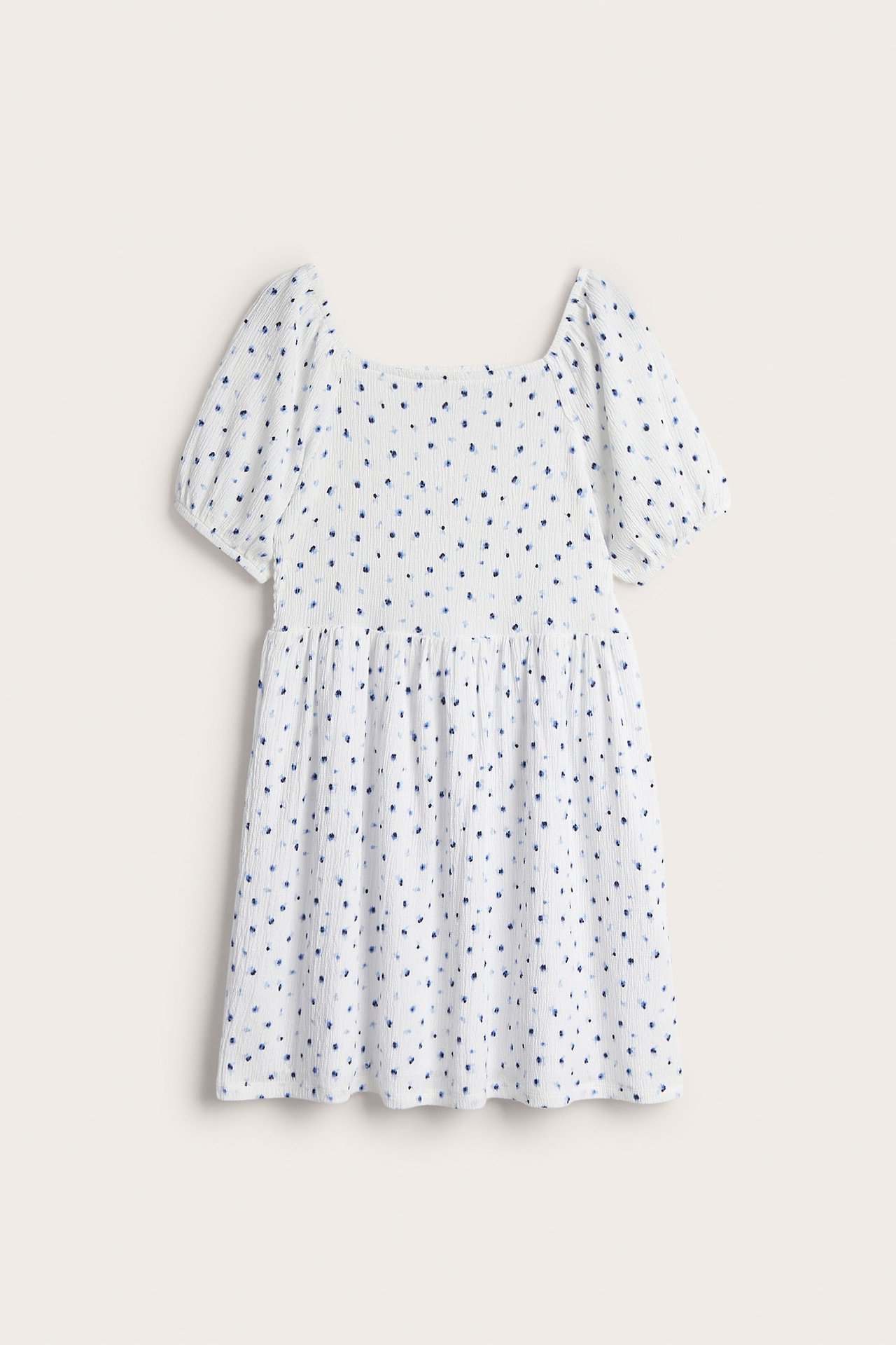 Frontvisning: Hvit krinklet jerseykjole for barn med firkantet hals, puffermer og blått prikkemønster.