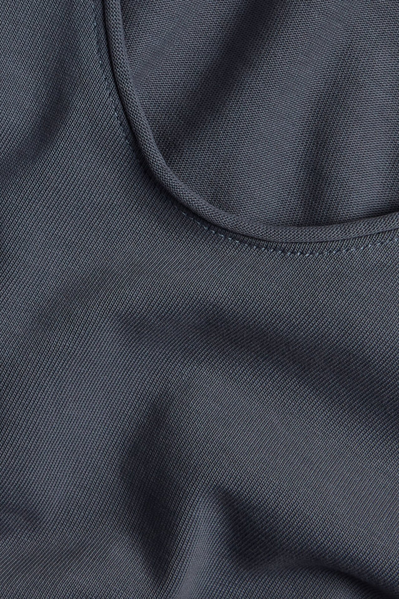 Nærbilde av en mørkeblå bomullsjersey-topp med rund hals.