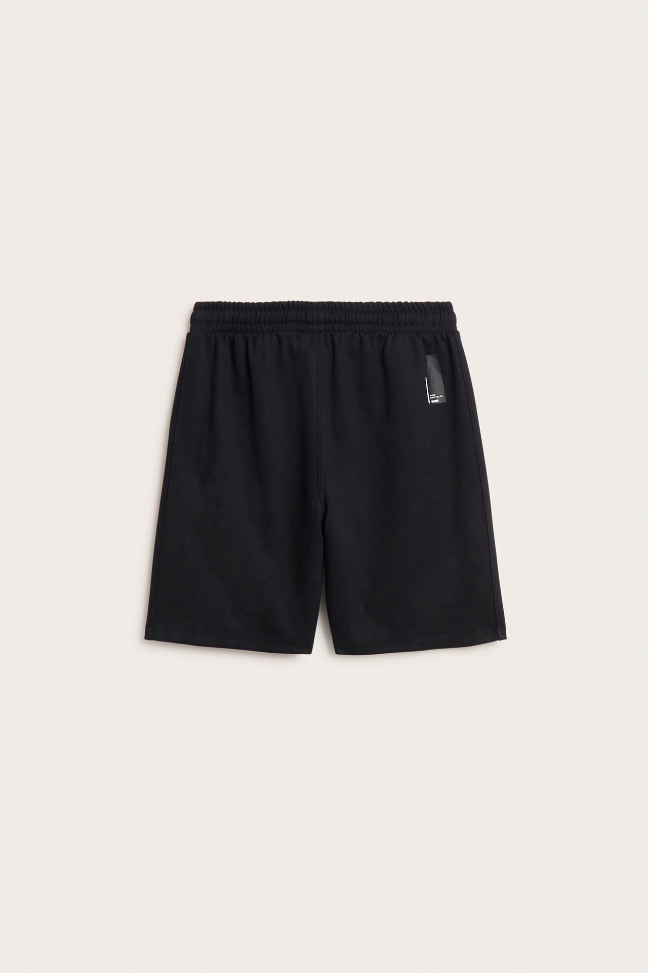 Framifrån, svarta interlockshorts med resår i midjan, dragsko och dolda sidfickor.