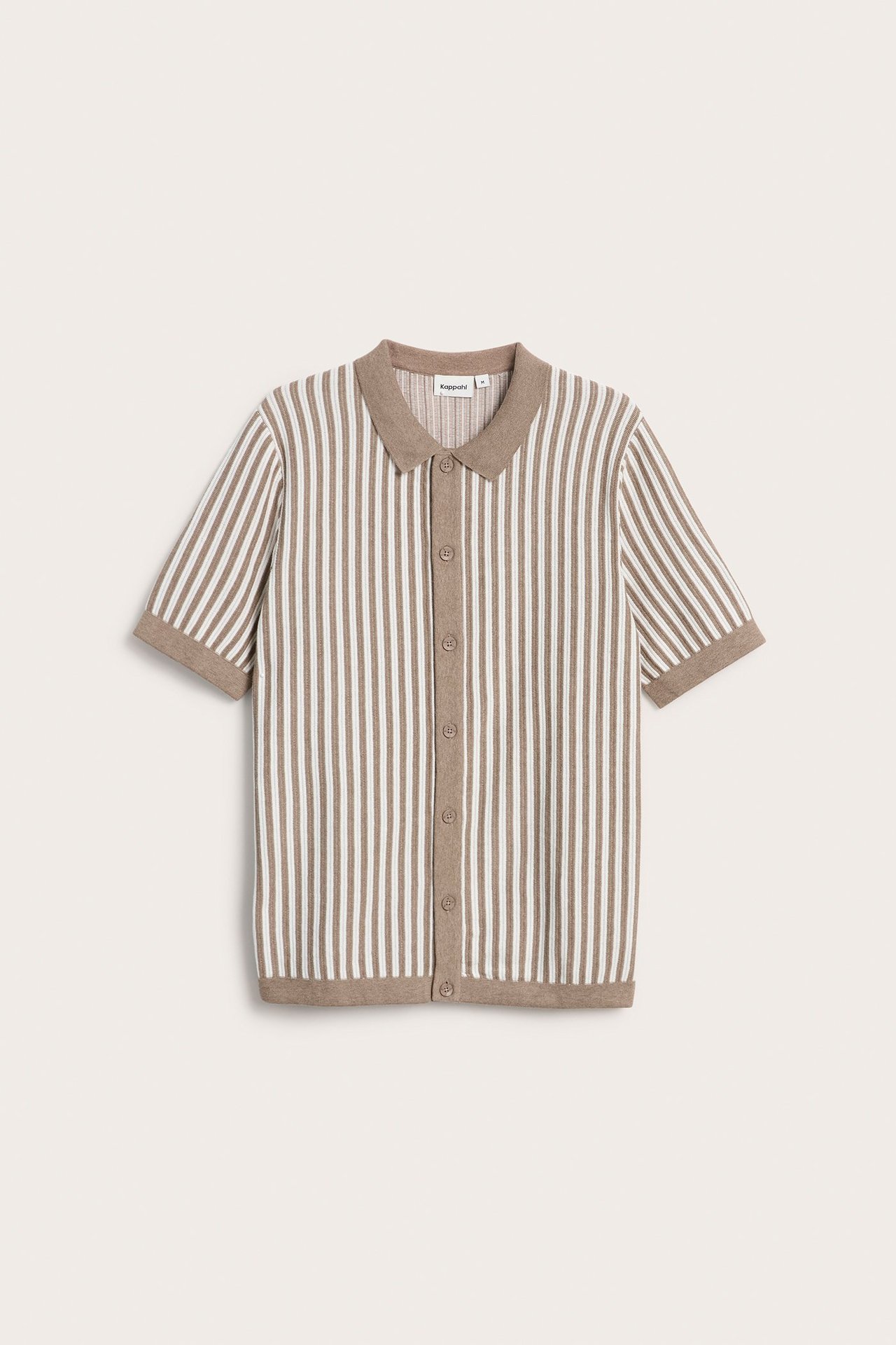 Edestä kuvattu beige-valkoraidallinen neulottu lyhythihainen pikeepaita, jossa on täysi nappikiinnitys.