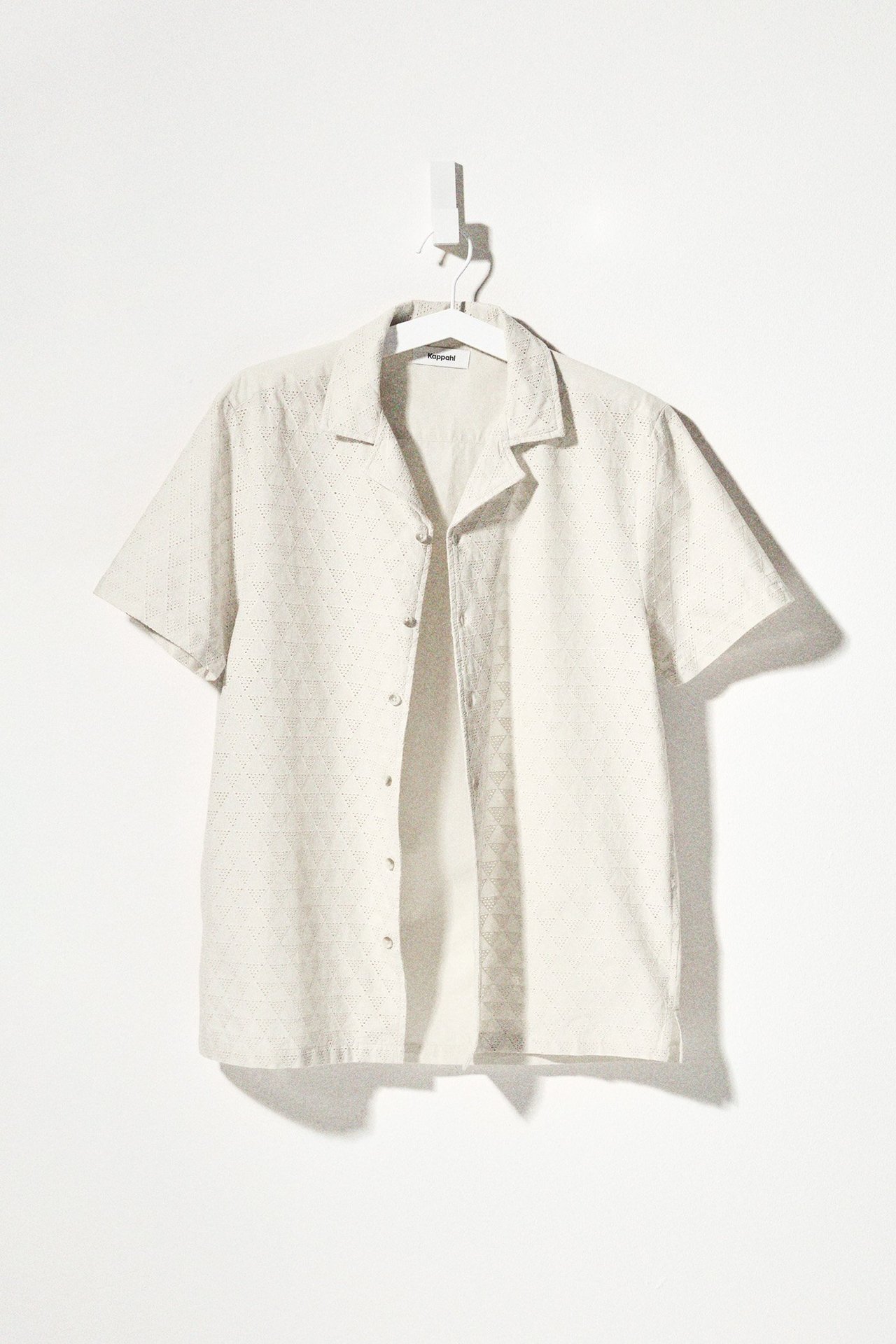 Edestä näkymä vaaleanbeigestä miesten lyhythihaisesta puuvillapaidasta, jossa broderie anglaise -kuvio, auki.