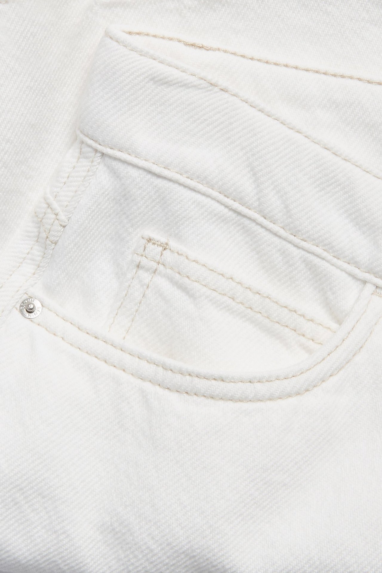 Zbliżenie białej bawełnianej spódnicy z twillu, z kieszenią, jasnymi szwami i metalowym nitem.