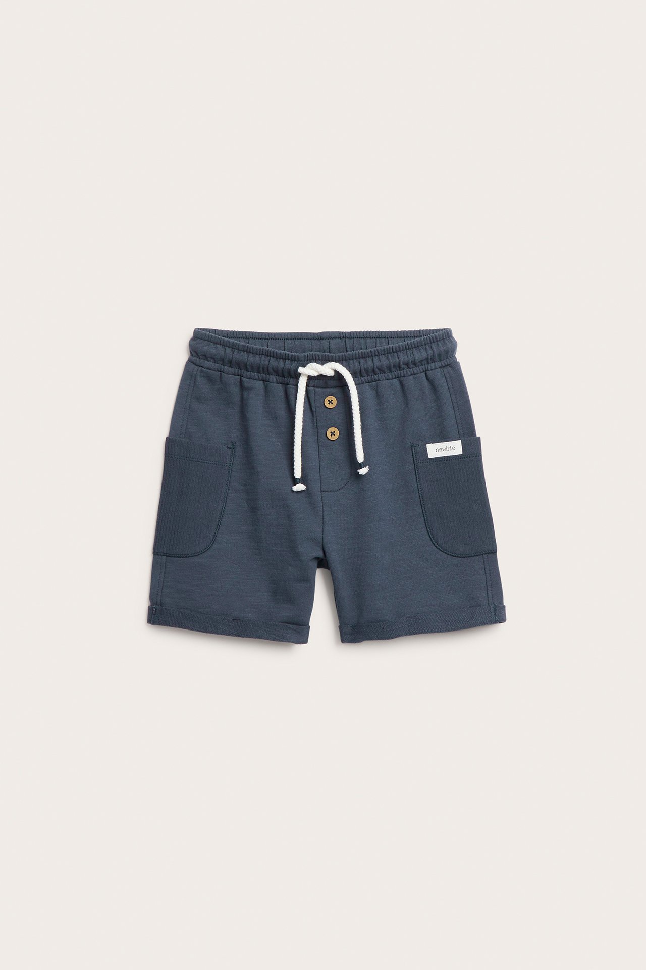 Frontvisning: Mørkeblå barneshorts i bomull med elastisk midje, hvit snøring, dekorative knapper og sidelommer.