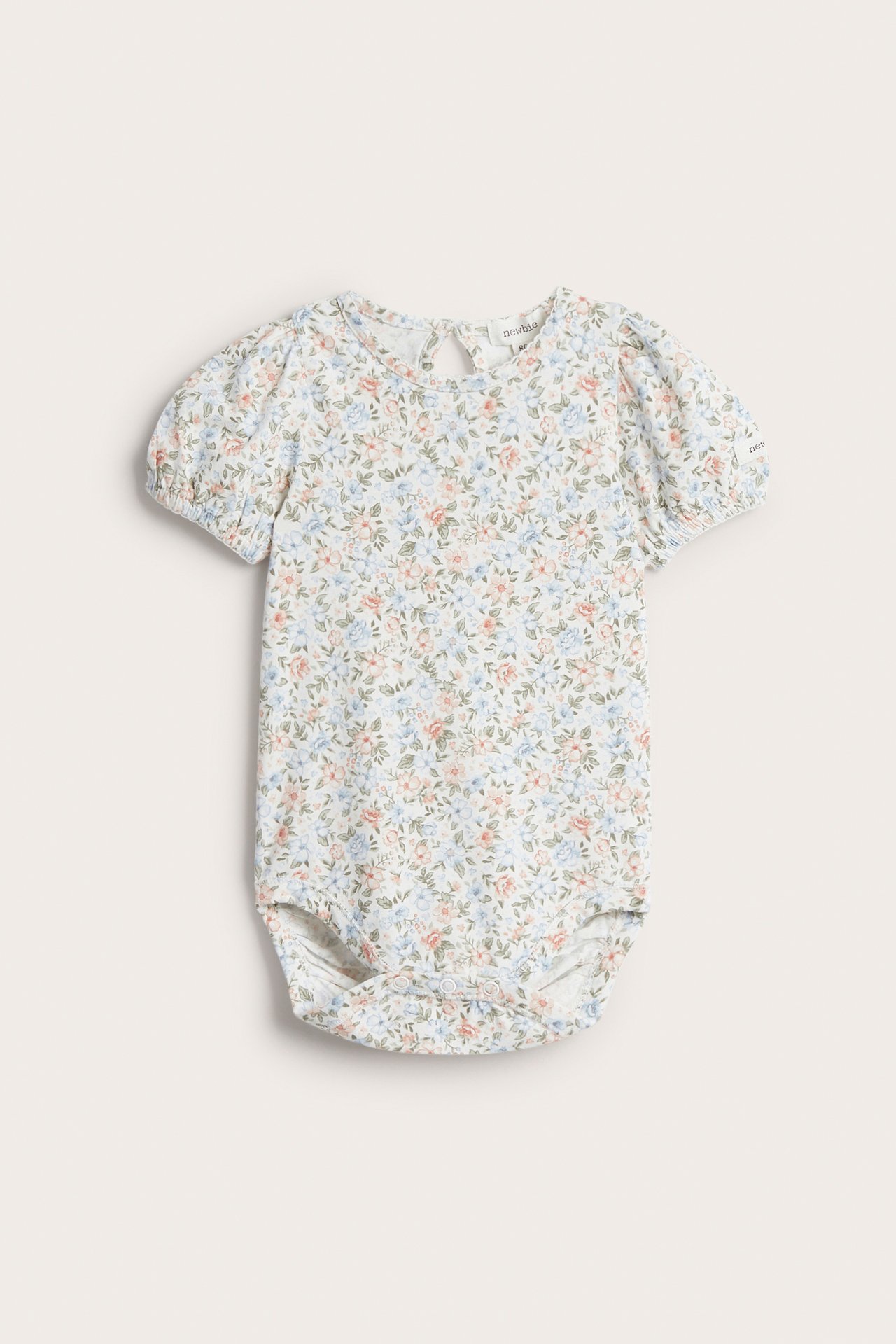Frontvisning: Offwhite babybody med småblomstret mønster, korte puffermer og trykknapper.