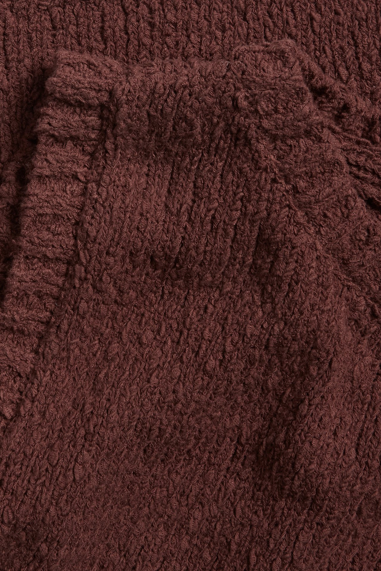 Nærbilde av en brun strikket topp med bouclé-effekt.