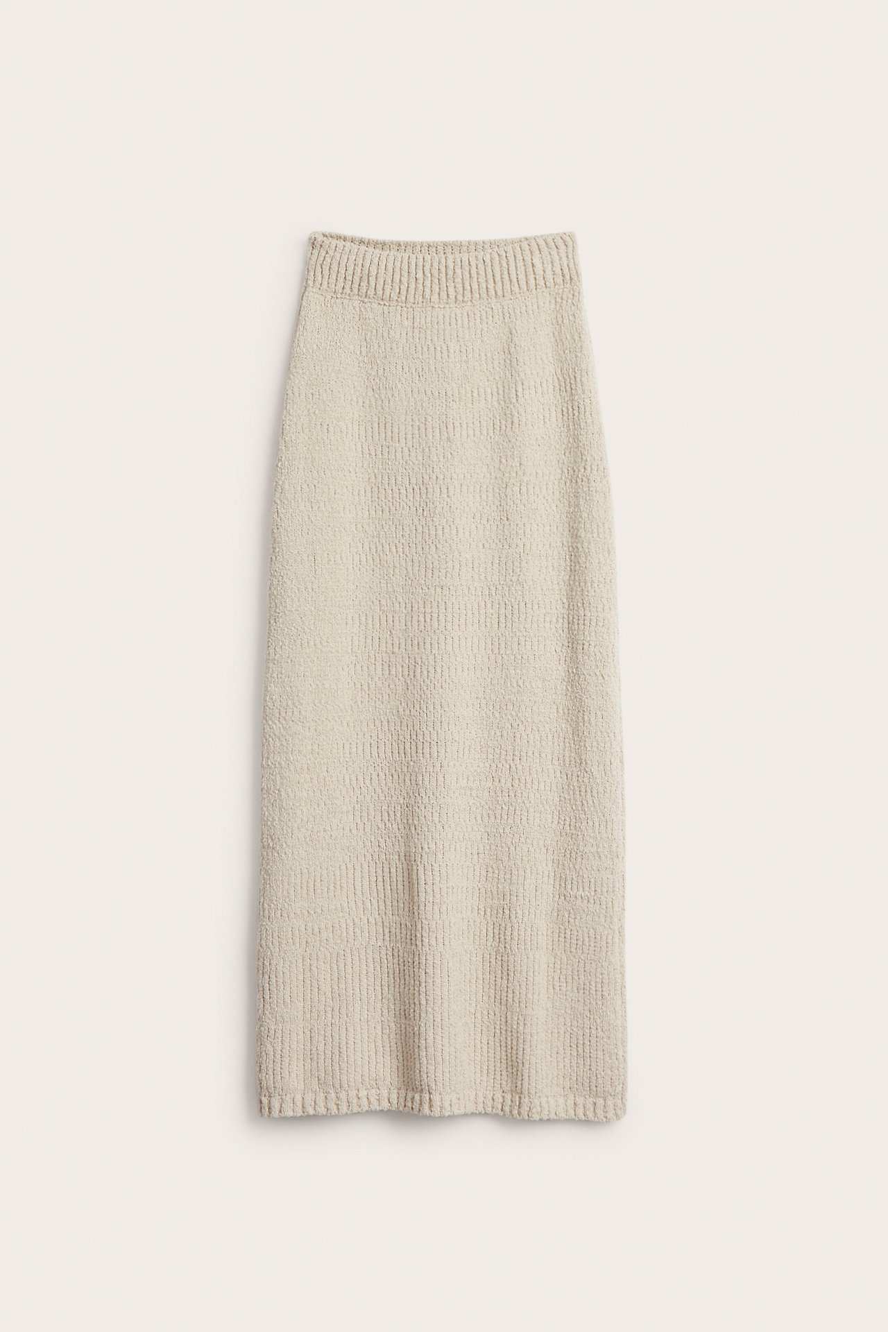 Frontvy av en ljusbeige stickad rak midikjol med resår i midjan och bouclégarn.