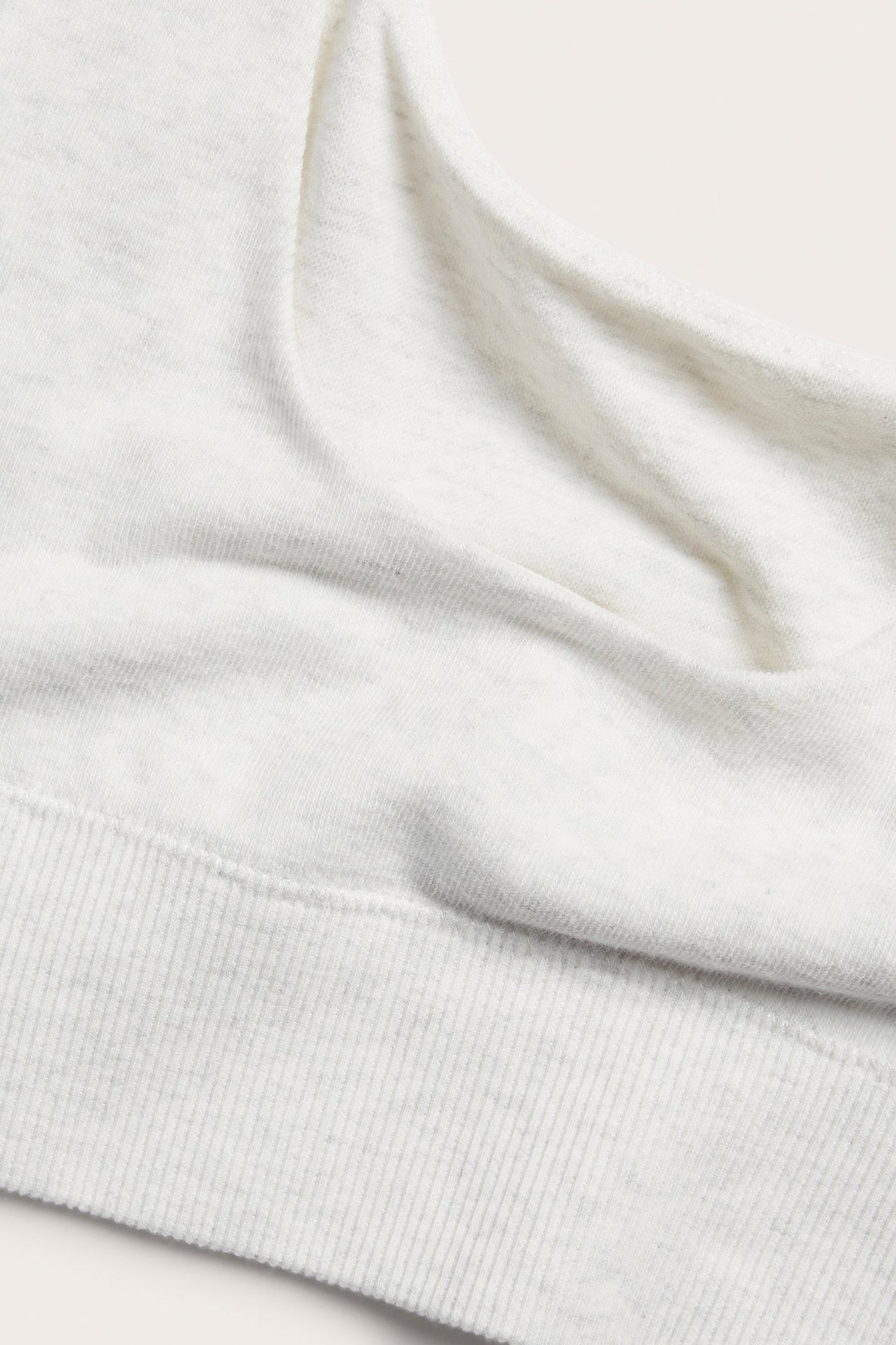 Zbliżenie białego melanżowego topu biustonosza z mieszanki bawełny z prążkowanym dołem.