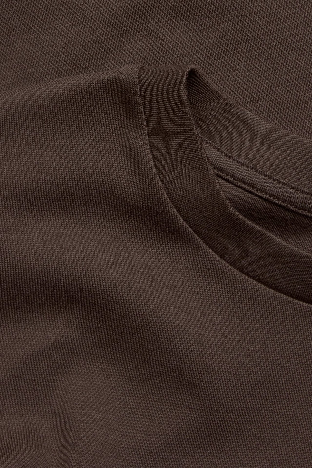 Zbliżenie na ciemnobrązowy, gładki bawełniany t-shirt z prążkowanym okrągłym dekoltem.