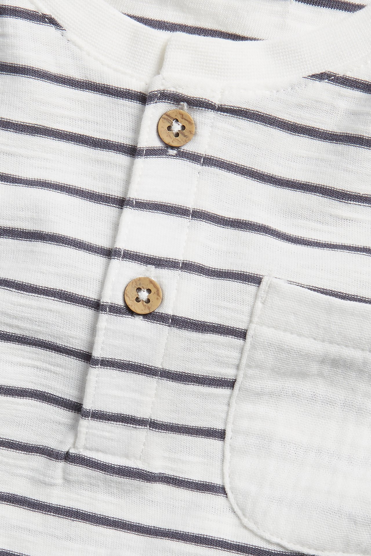 Närbild på en offwhite randig t-shirt i bomull med knappslå och bröstficka.