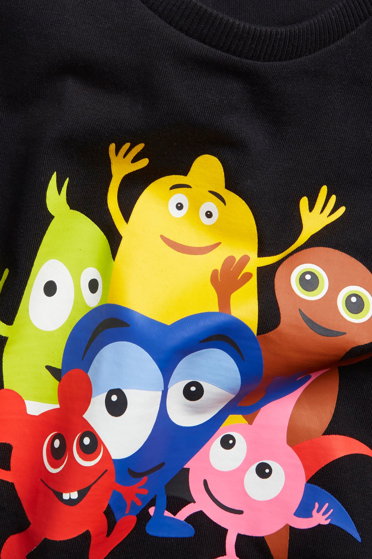 Zbliżenie na czarny bawełniany T-shirt dziecięcy z kolorowym nadrukiem postaci Babblarna z przodu.