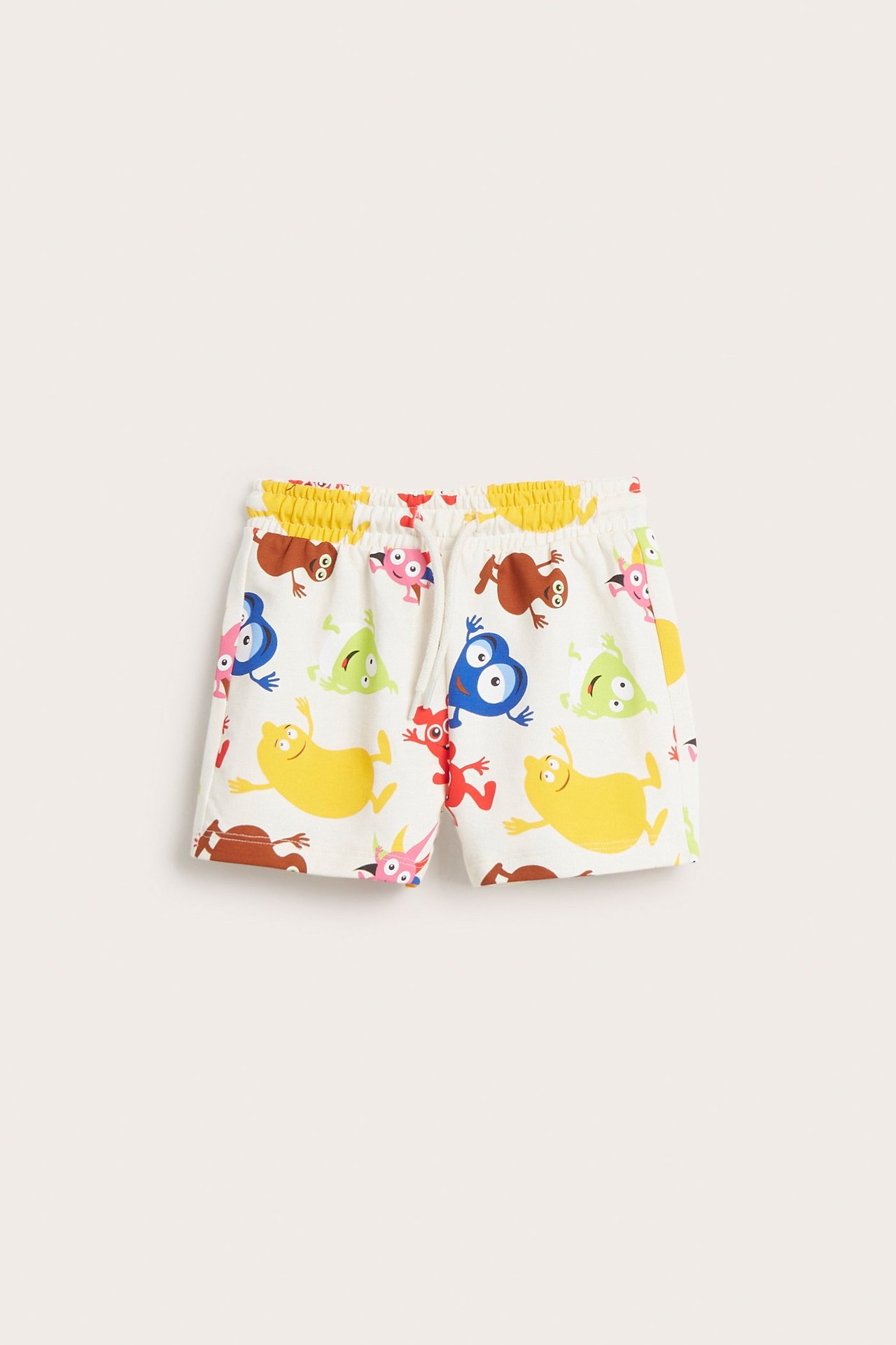 Edestä: Lasten luonnonvalkoiset puuvillaiset college-shortsit värikkäällä Babblarna-kuviolla ja joustovyötäröllä.