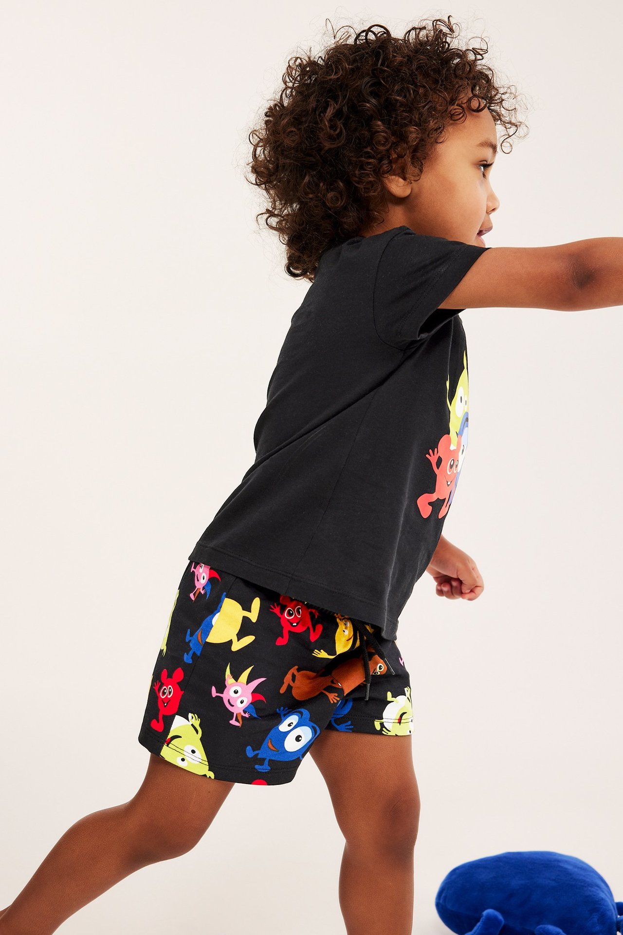 Sivukuva lapsesta mustissa kuvioiduissa Babblarna-collegeshortseissa ja mustassa t-paidassa.