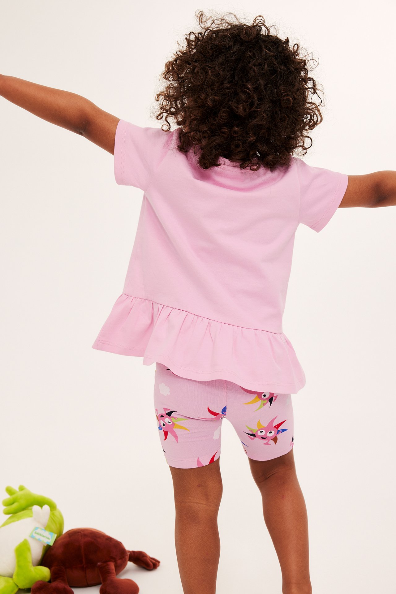 Bakfra: et barn i rosa mønstrede Babblarna sykkelshorts og en rosa topp med volang.