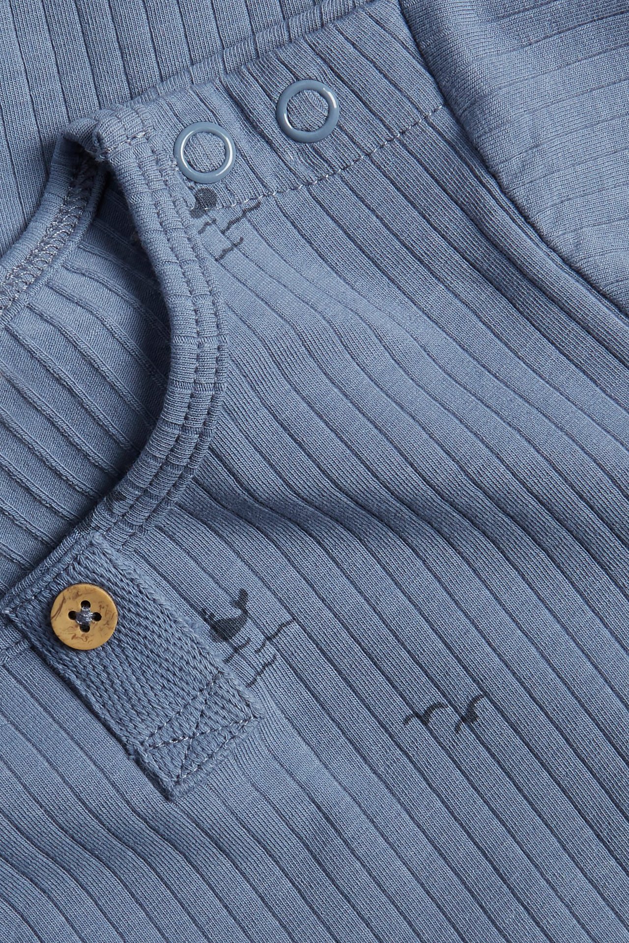 Zbliżenie: Niebieskie prążkowane body niemowlęce z krótkim rękawem, morskim wzorem, zatrzaskami i ozdobnym guzikiem.