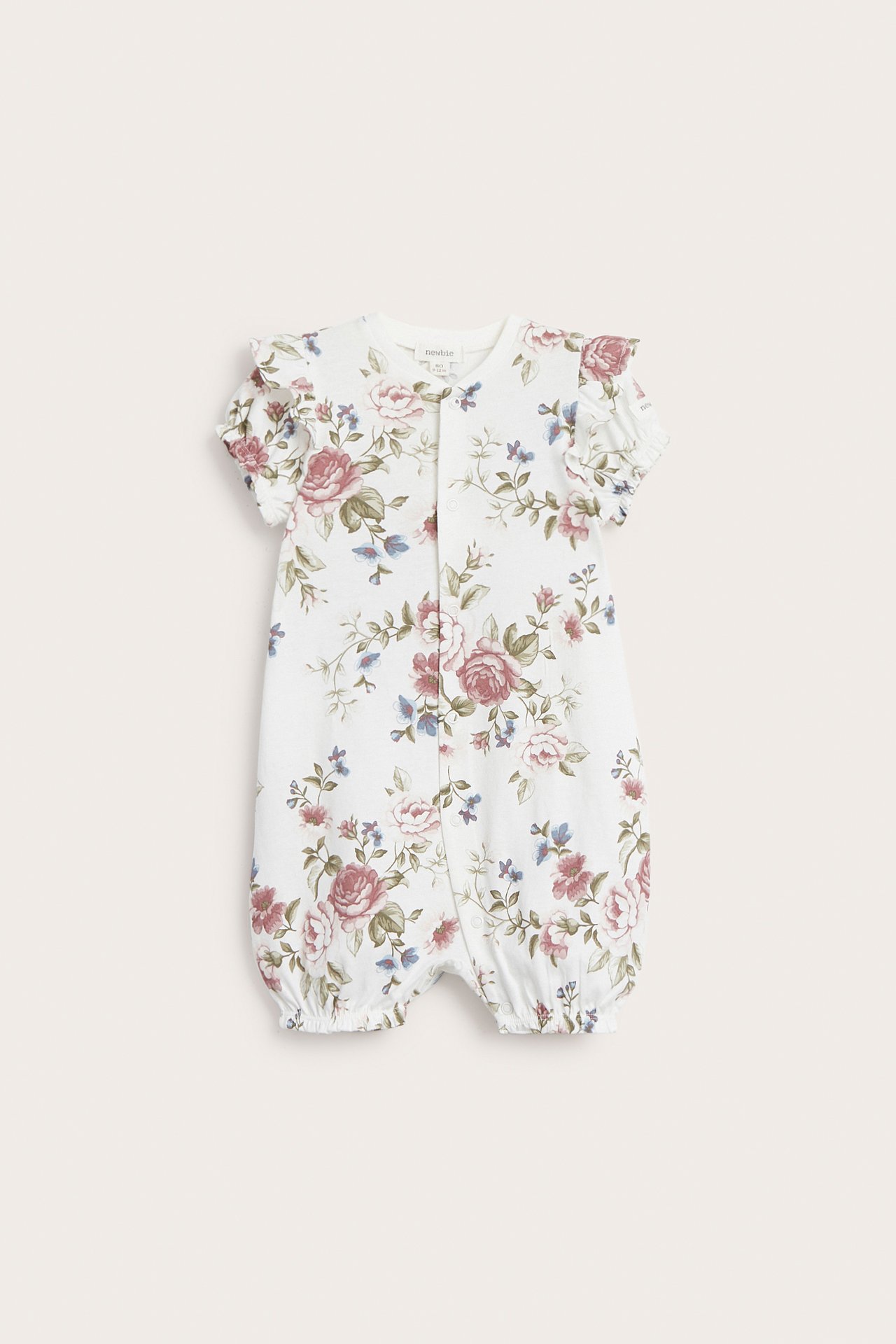 Frontvy: Offwhite bomulls-babypyjamas med korta volangärmar, korta ben och rosa blommönster.