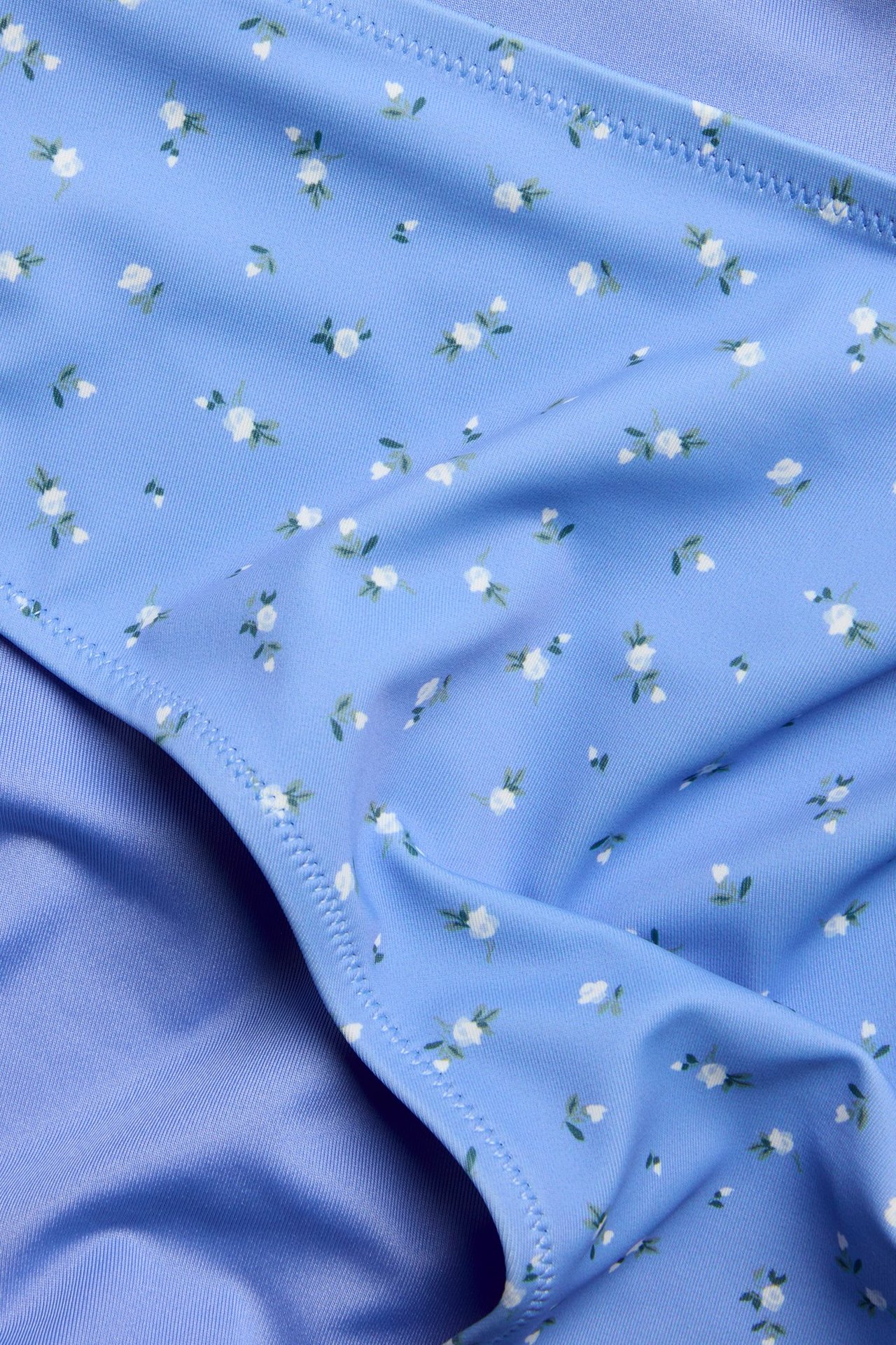 Nærbilde av en blå mønstret bikinitruse med små hvite blomstermønster.