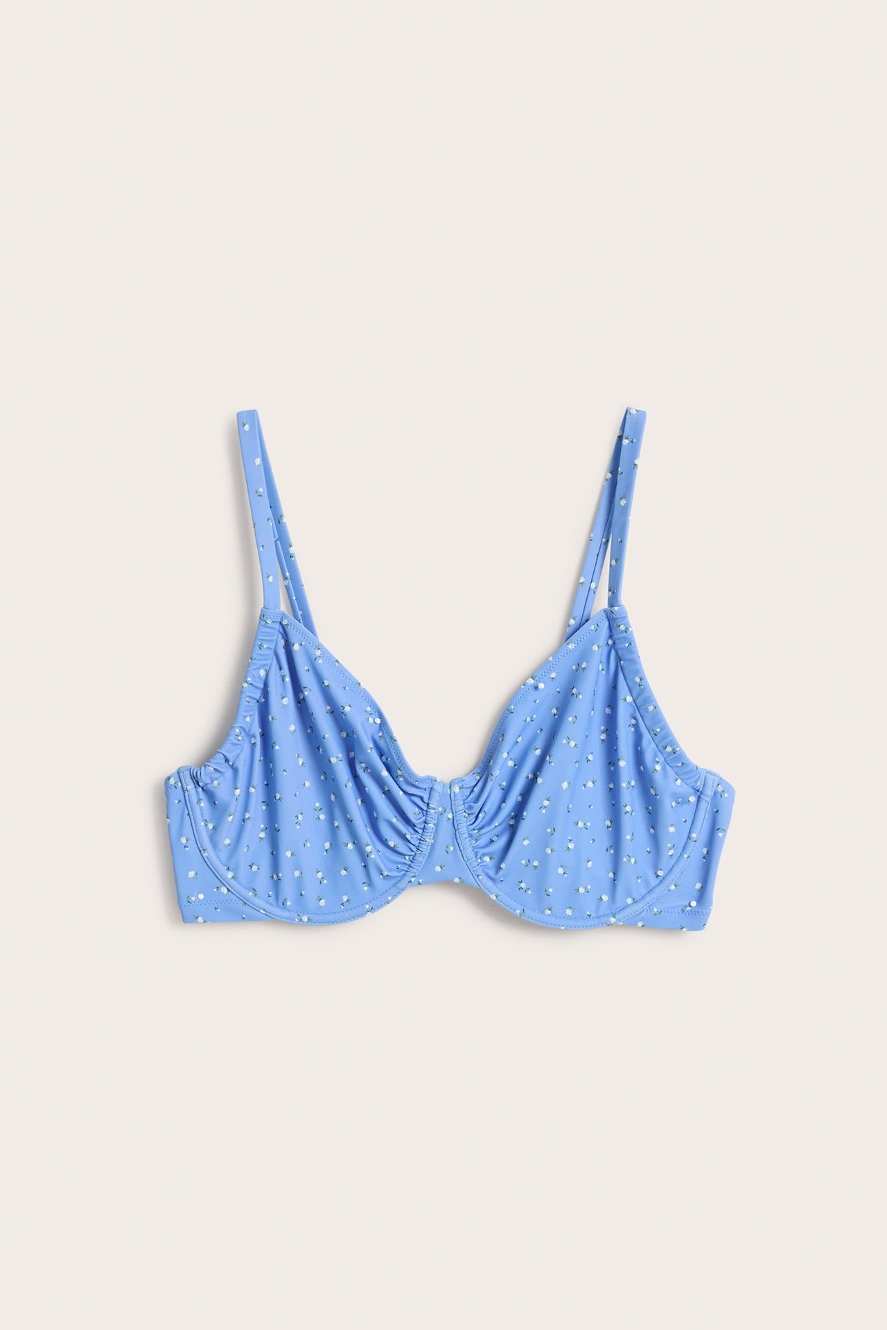 Widok z przodu niebieskiego wzorzystego biustonosza bikini z fiszbinami, małymi białymi kwiatami, regulowanymi ramiączkami.