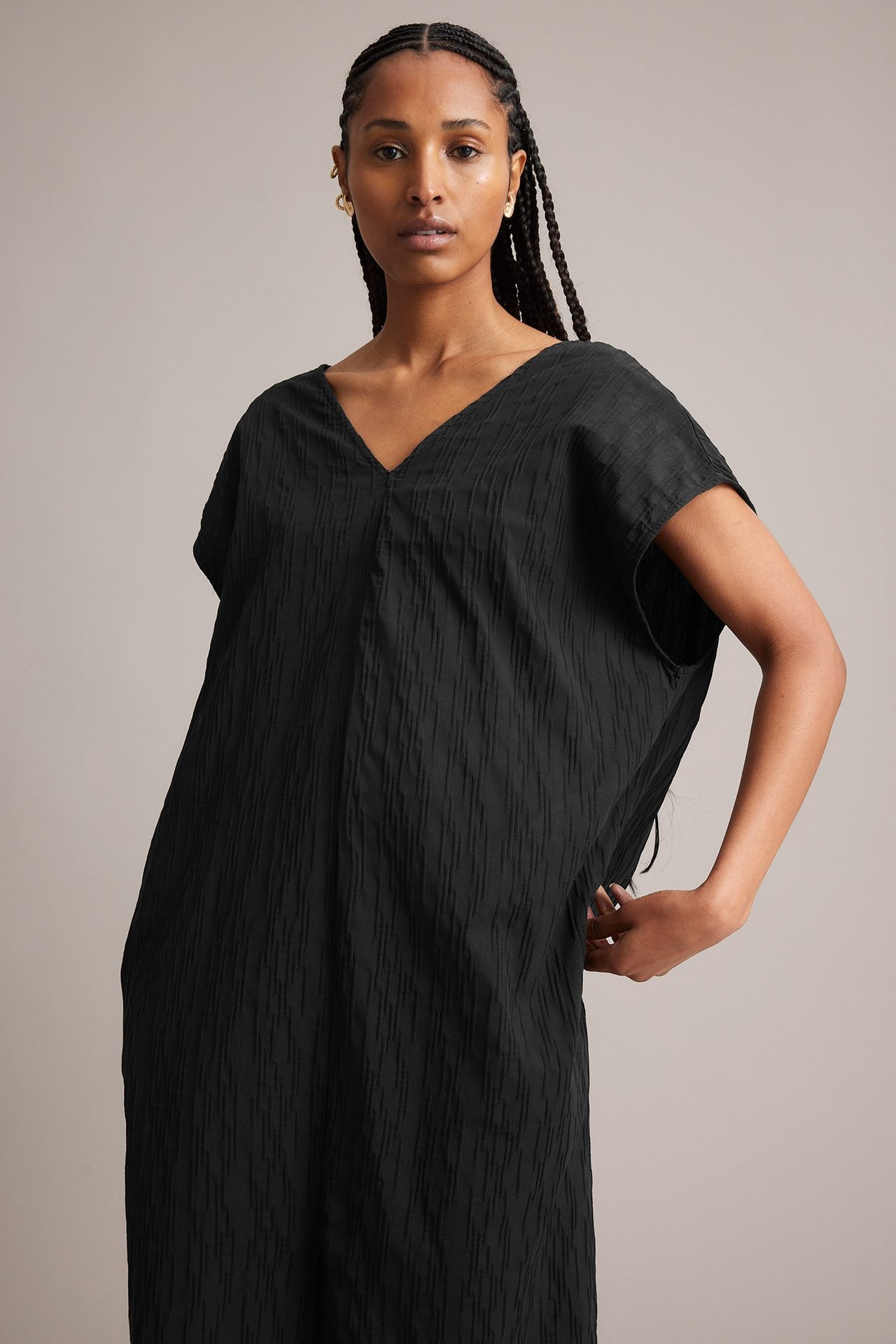 Forfra, kvinne i svart krøllet bomullsblandingskjole med V-hals og løs passform.