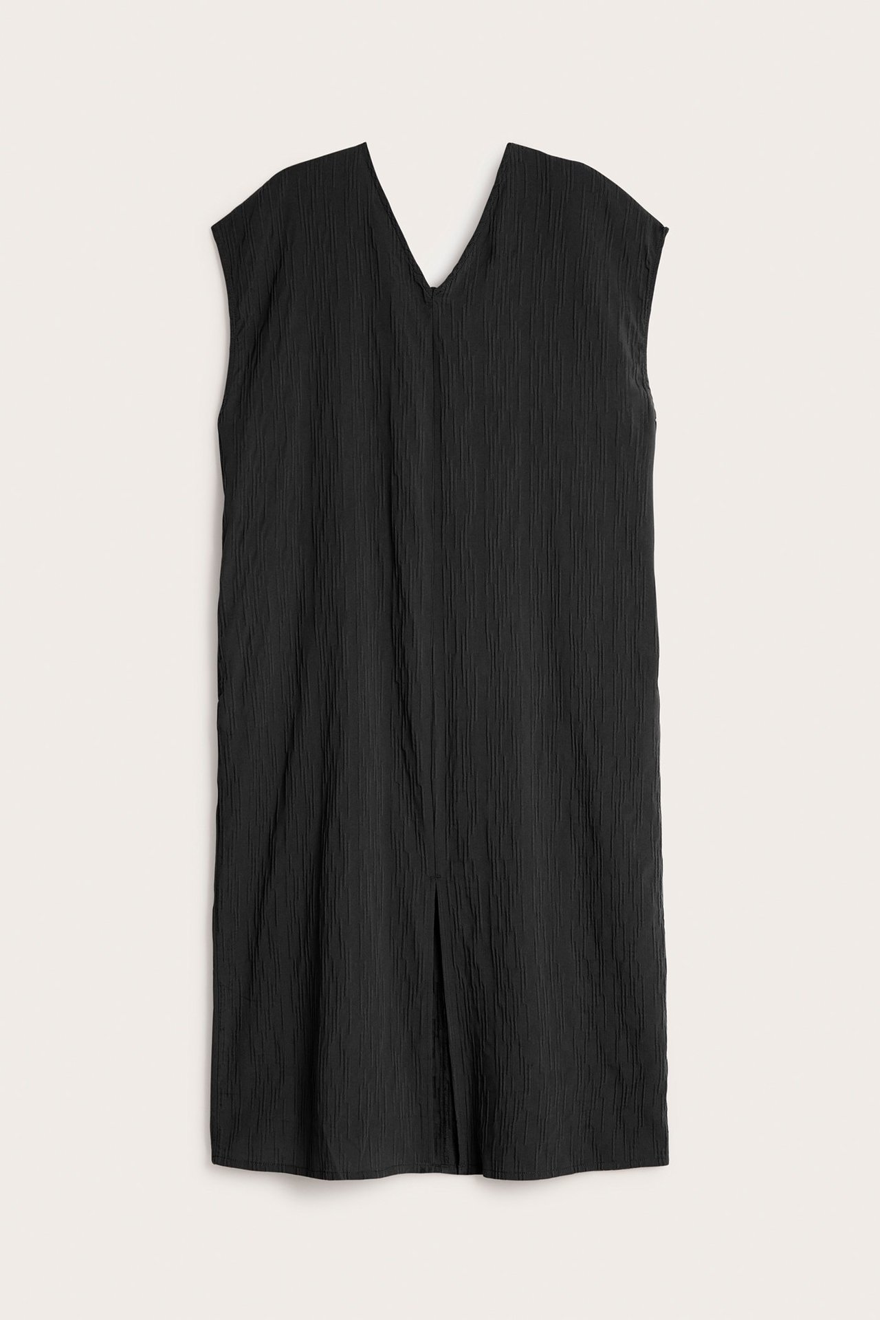 Frontvisning av en svart krøllet ermeløs kjole med V-hals og en liten splitt foran.