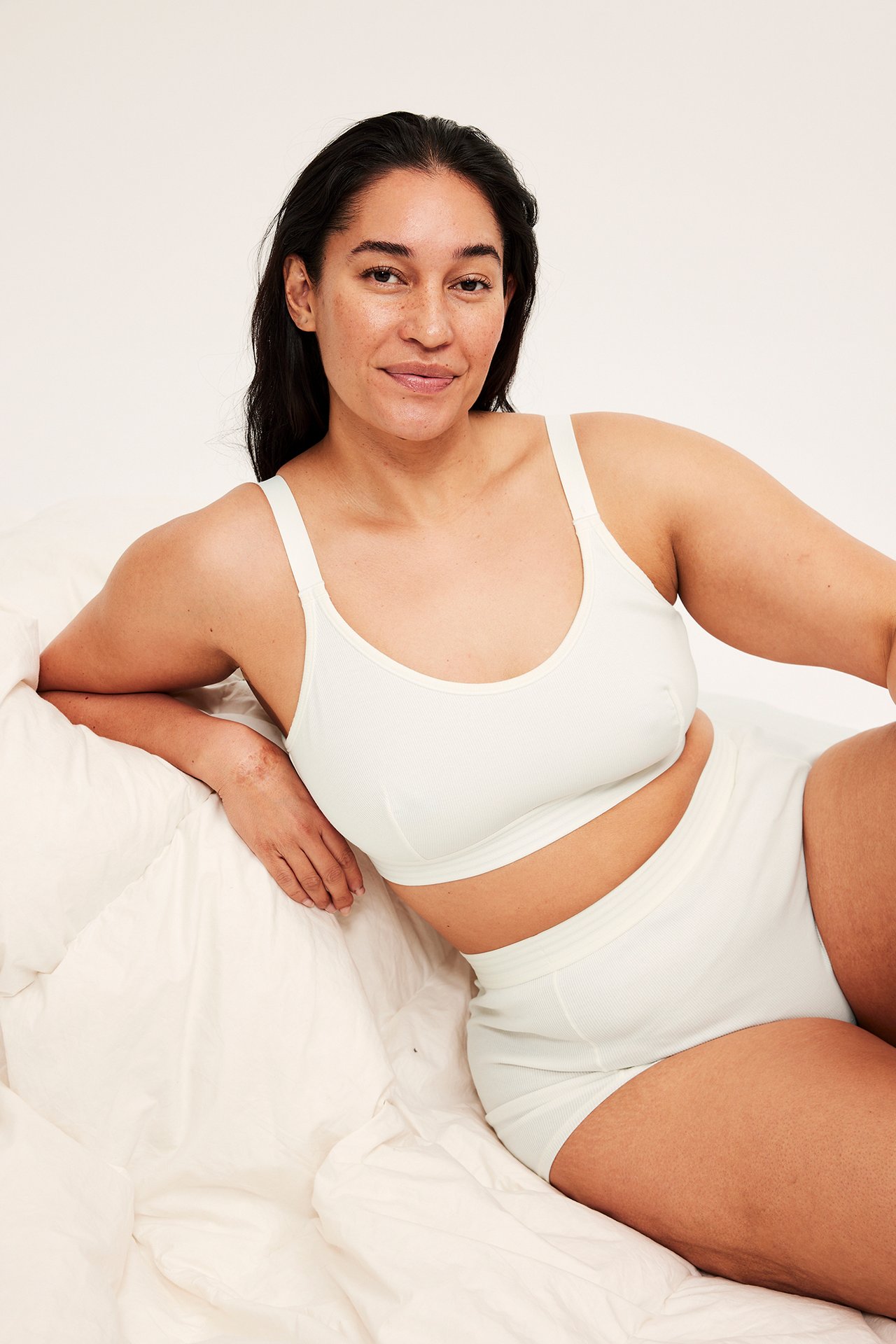 Forfra, kvinne i offwhite ribbet bøylefri BH og matchende ribbet boxershorts.