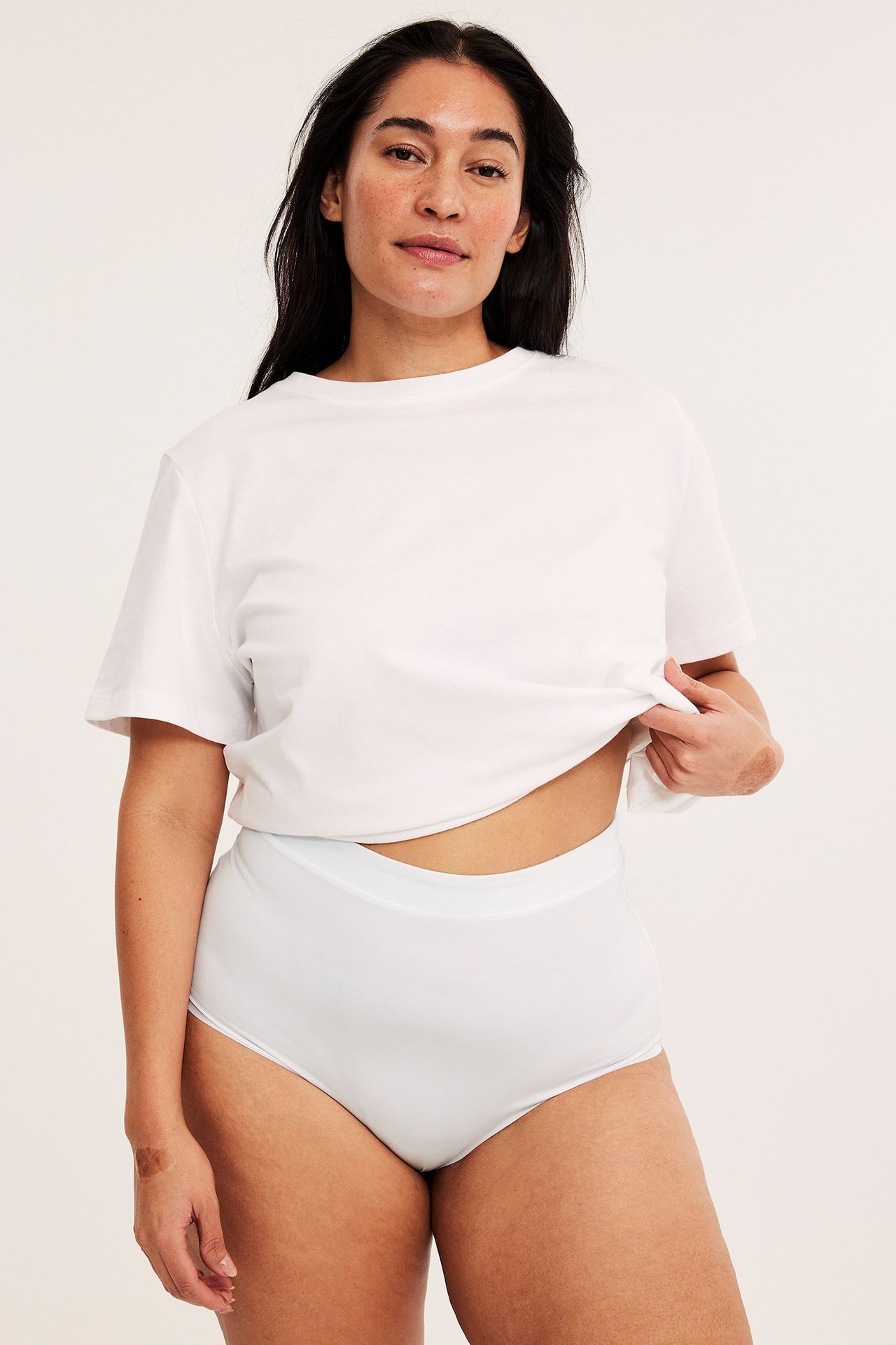 Forfra: Kvinne i hvite sømløse hipster-truser med strikk i midjen og en hvit t-skjorte.