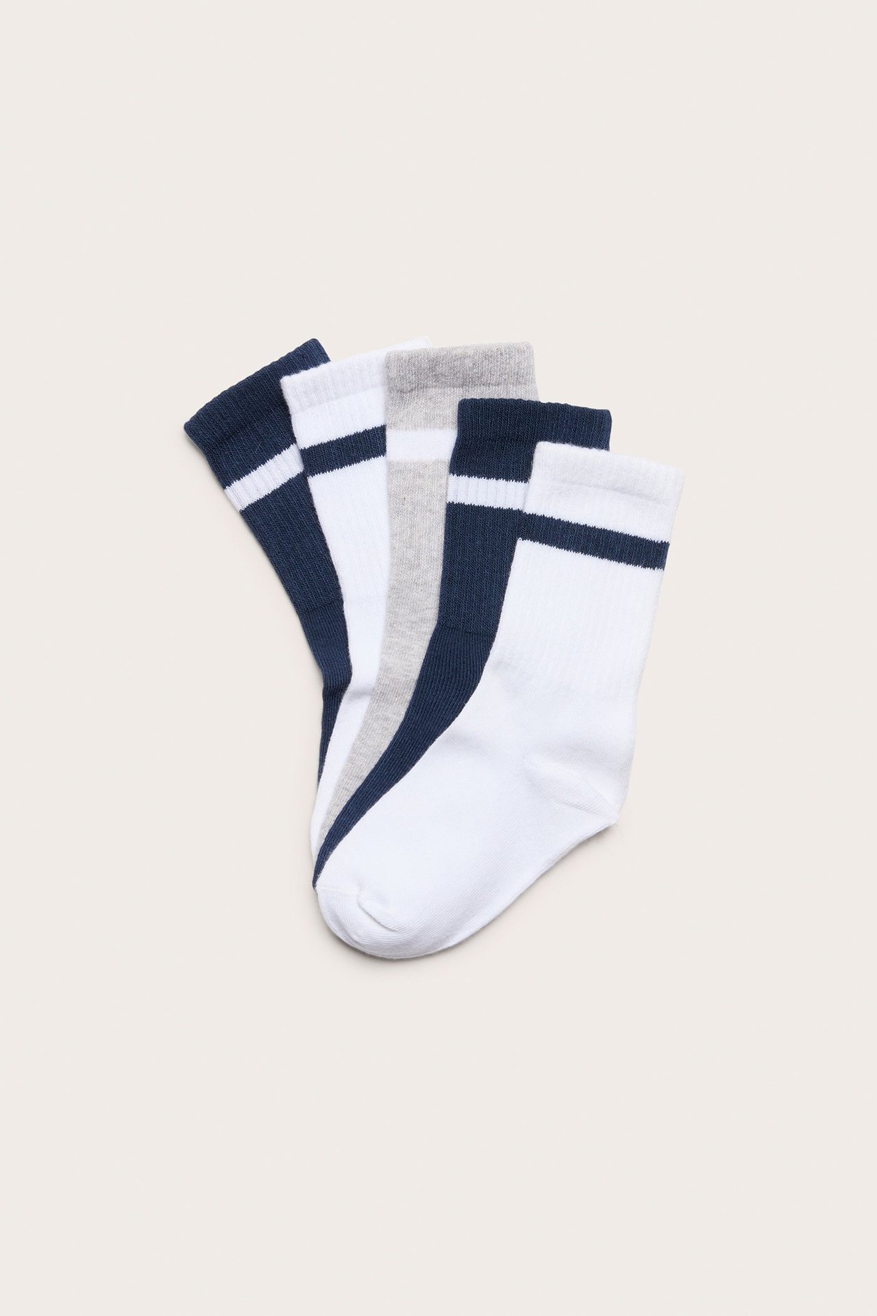 Widok z góry na trzy pary dziecięcych skarpet sportowych: granatowe, białe i jasnoszare, z paskami i ściągaczami.