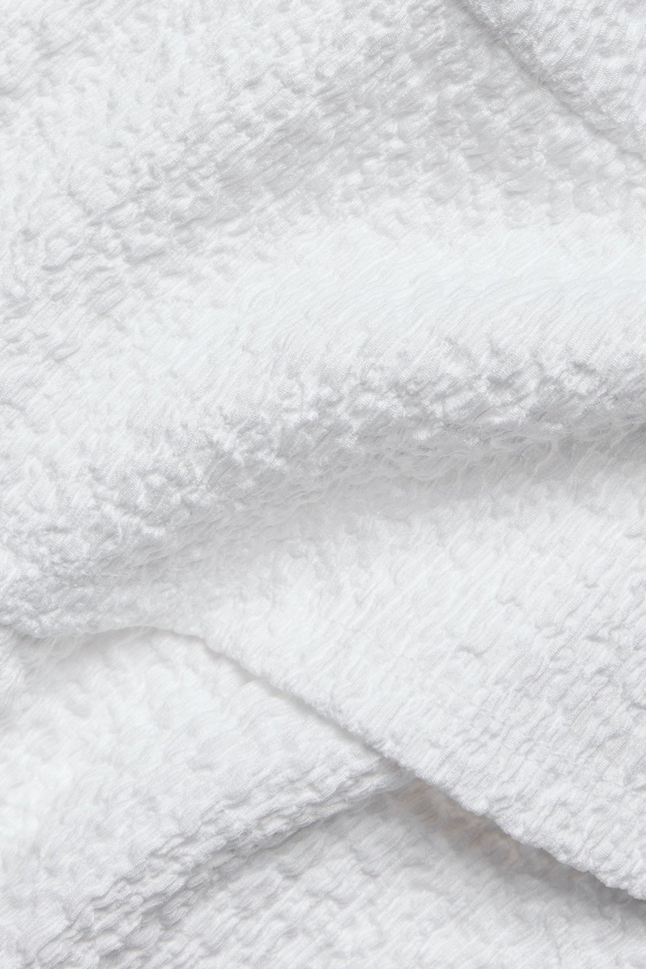 Närbild av vitt strukturerat jerseymaterial, del av en topp.