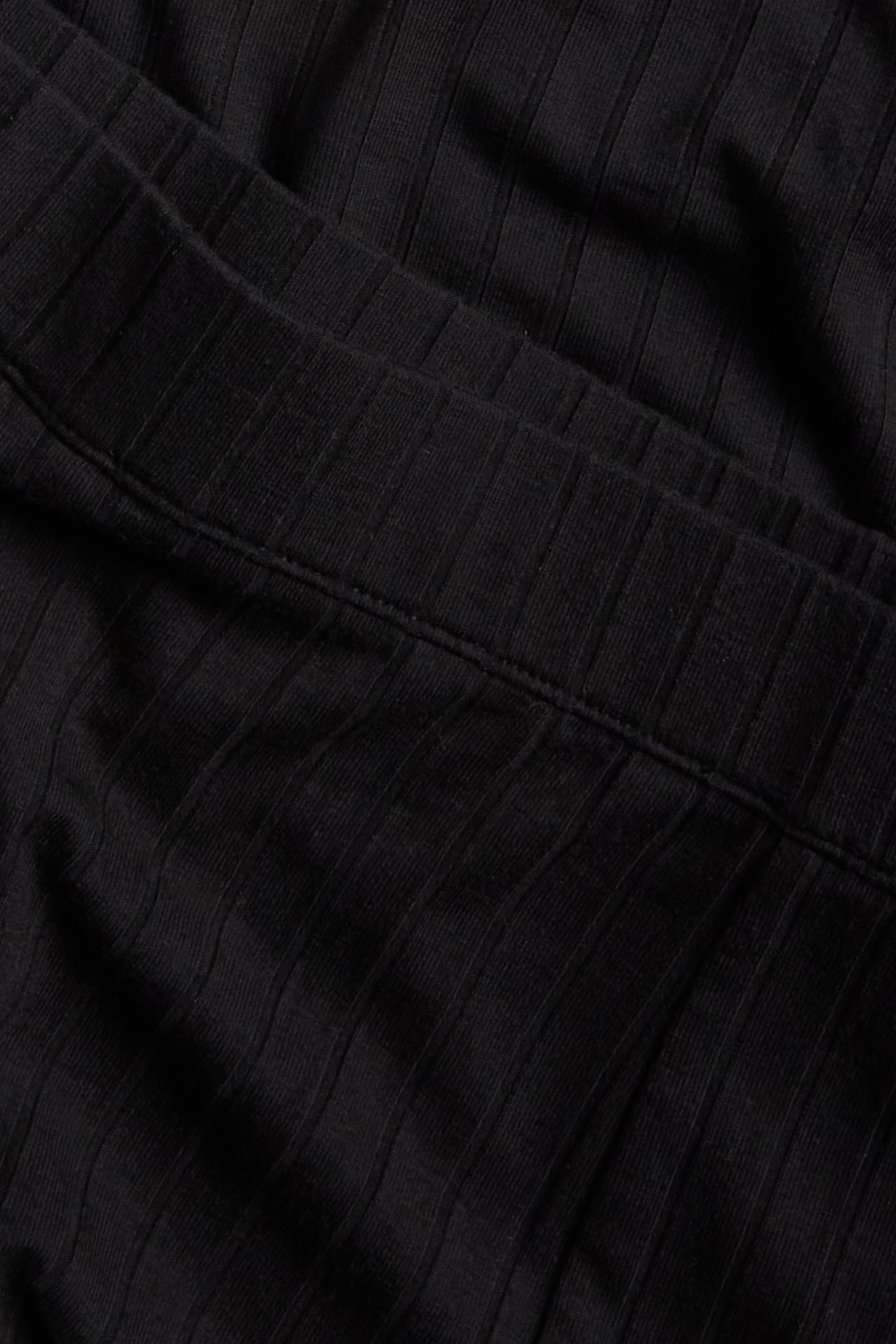 Närbild av svarta ribbade jersey shorts, visar den ribbade texturen och en söm.