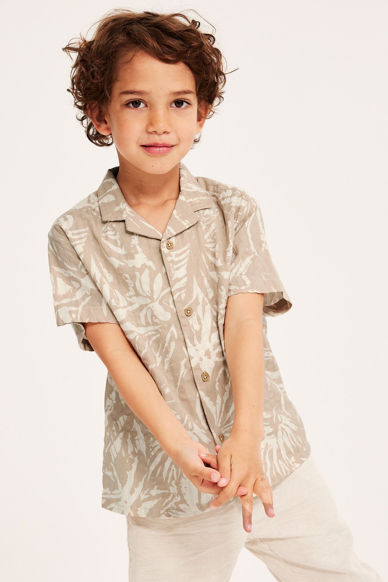 Widok z przodu: dziecko w jasnobeżowej koszuli seersucker we wzory i jasnobeżowych spodniach.