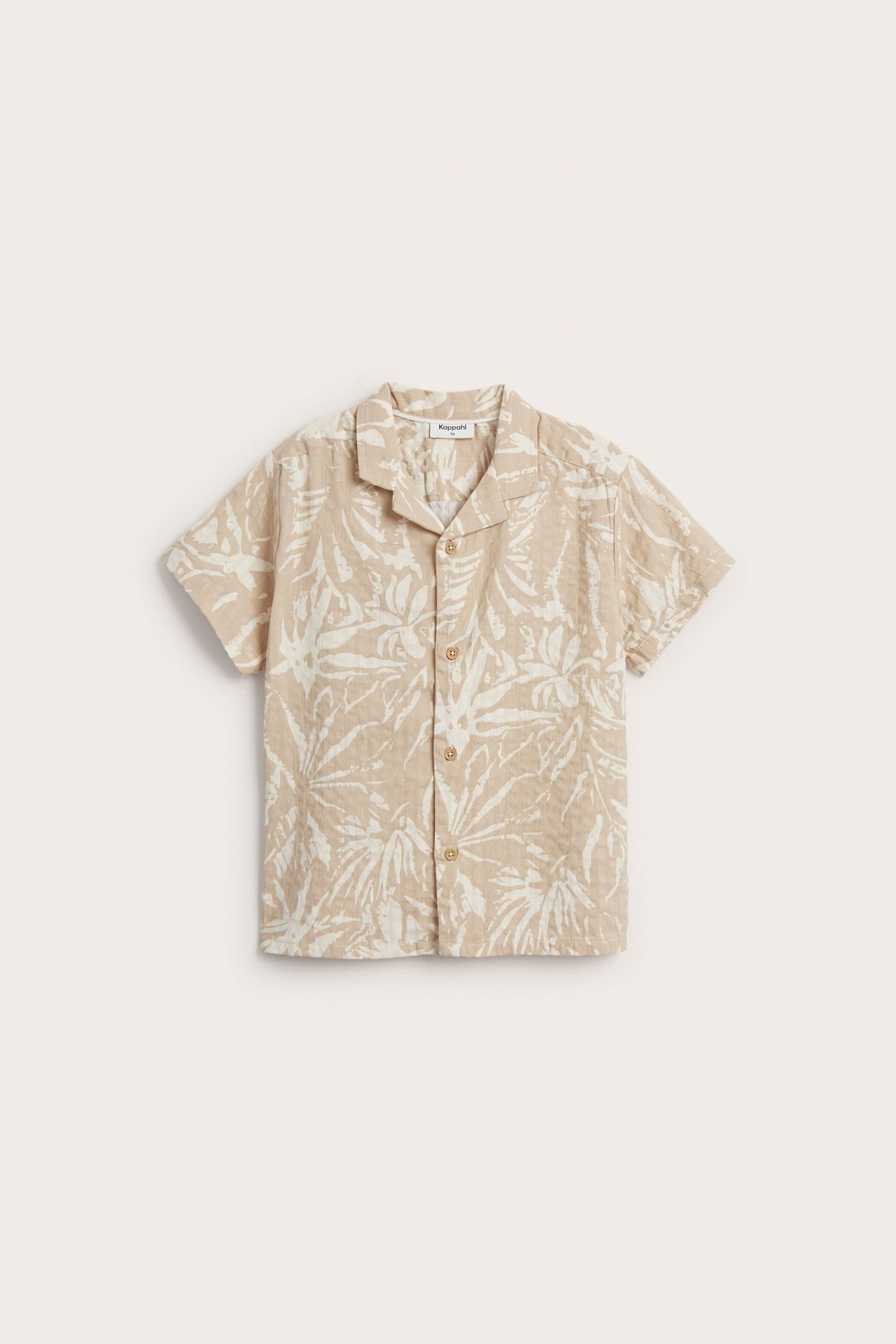 Widok z przodu: dziecięca jasnobeżowa koszula seersucker z białym wzorem liści i guzikami.