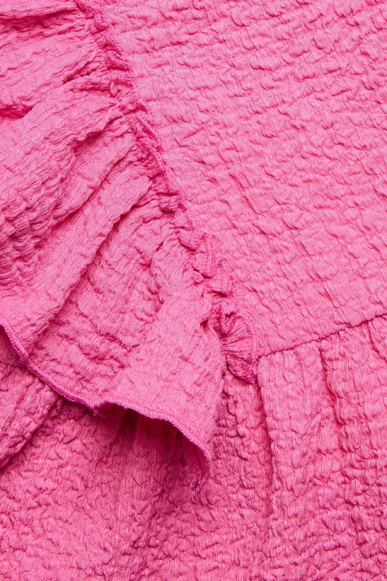 Zbliżenie różowego, strukturalnego topu z dżerseju z dużymi falbanami.