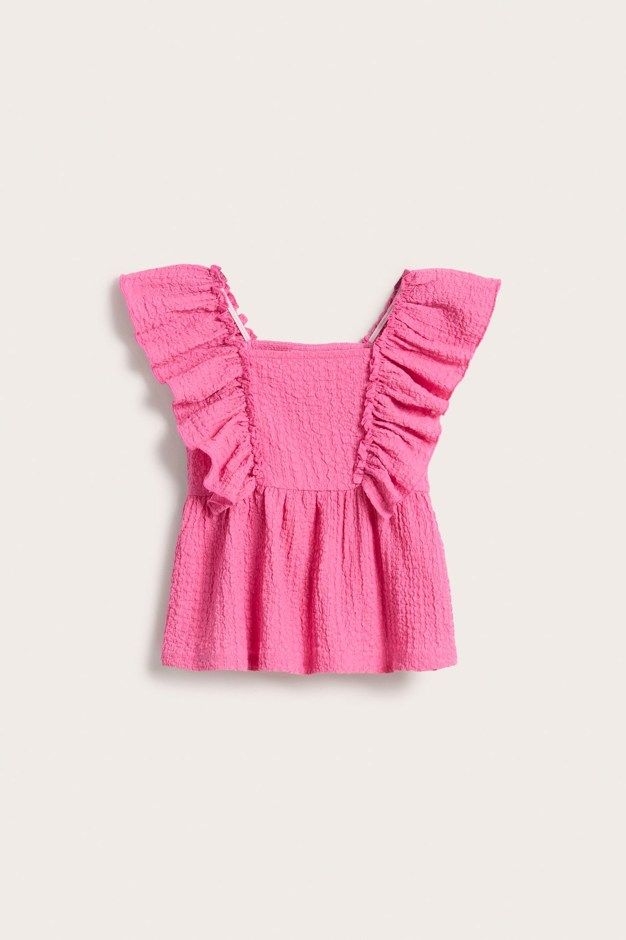 Widok z przodu różowego topu dziecięcego z teksturowanej dzianiny, z kwadratowym dekoltem i dużymi falbanami.