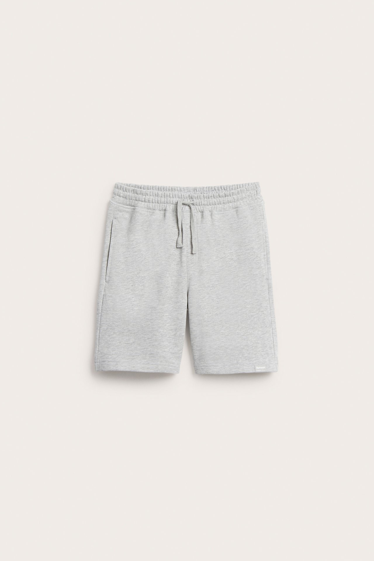 Frontvy av ljusgrå mjukisshorts i bomullsblandning med resår i midjan, dragsko och sidofickor.