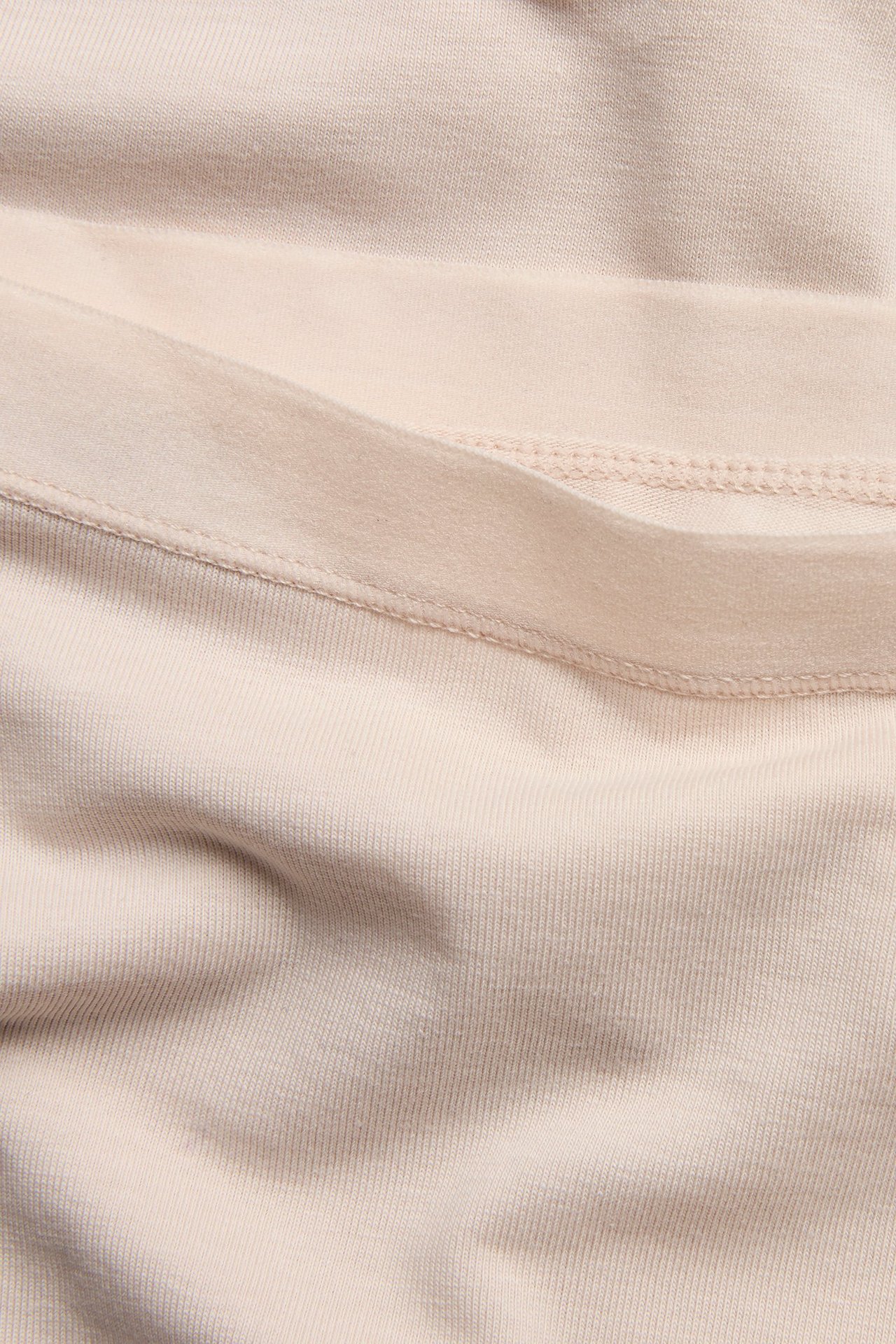 Zbliżenie na jasnobeżowe szorty z bawełny i elastanu z miękką gumką w pasie.