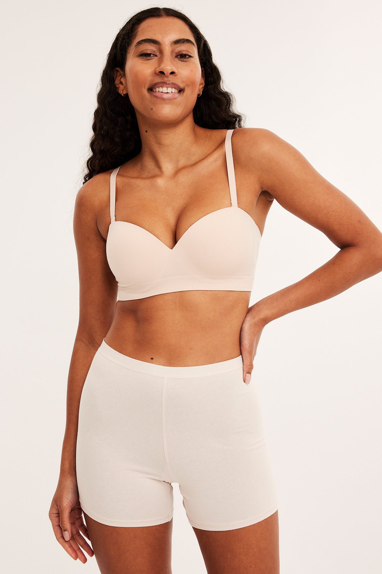 Forfra: kvinne i høytlivs lys beige bomulls-shorts og matchende BH.