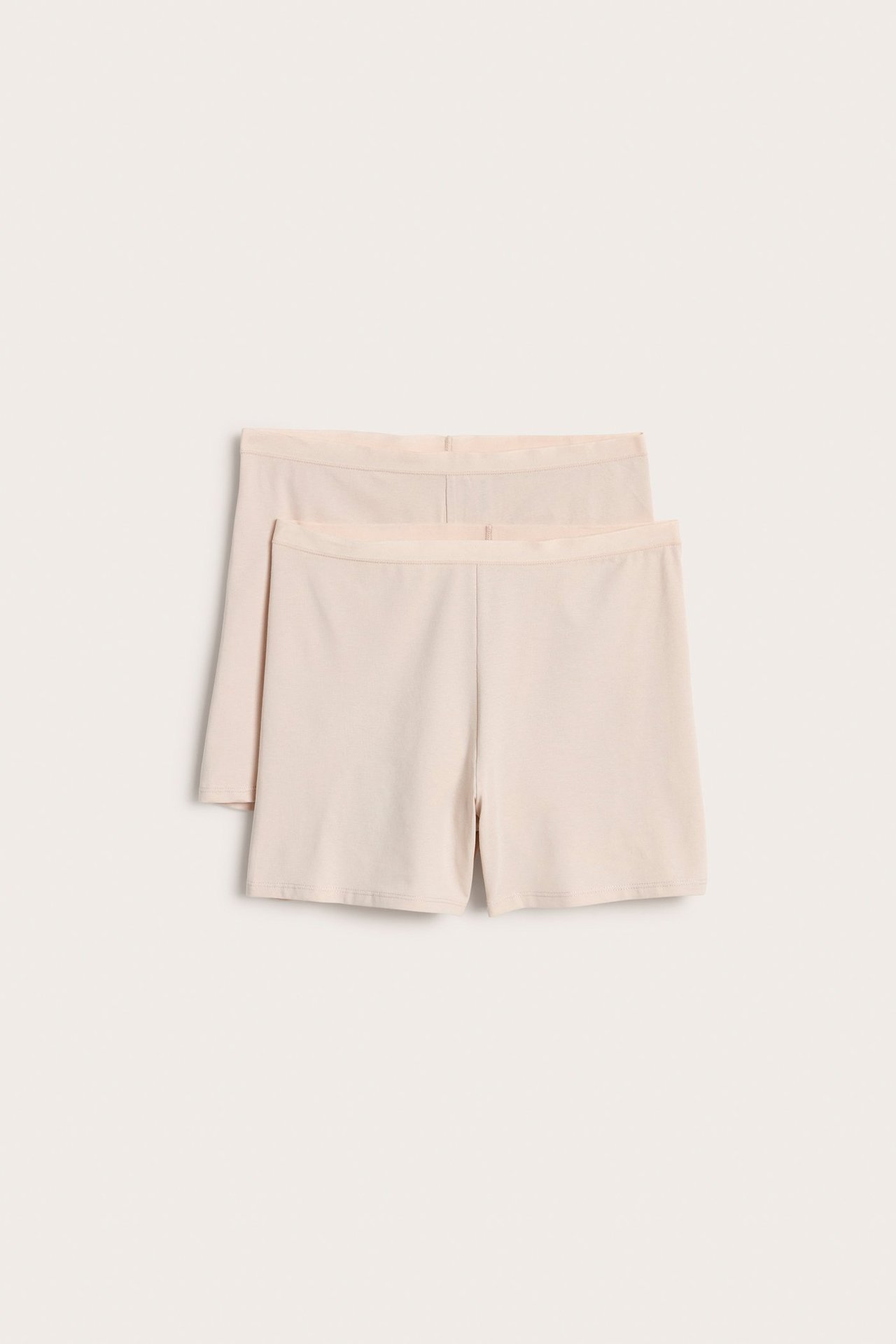 Frontvisning av to lysbeige høy-midje shorts-truser i bomullsblanding med myk elastisk linning.