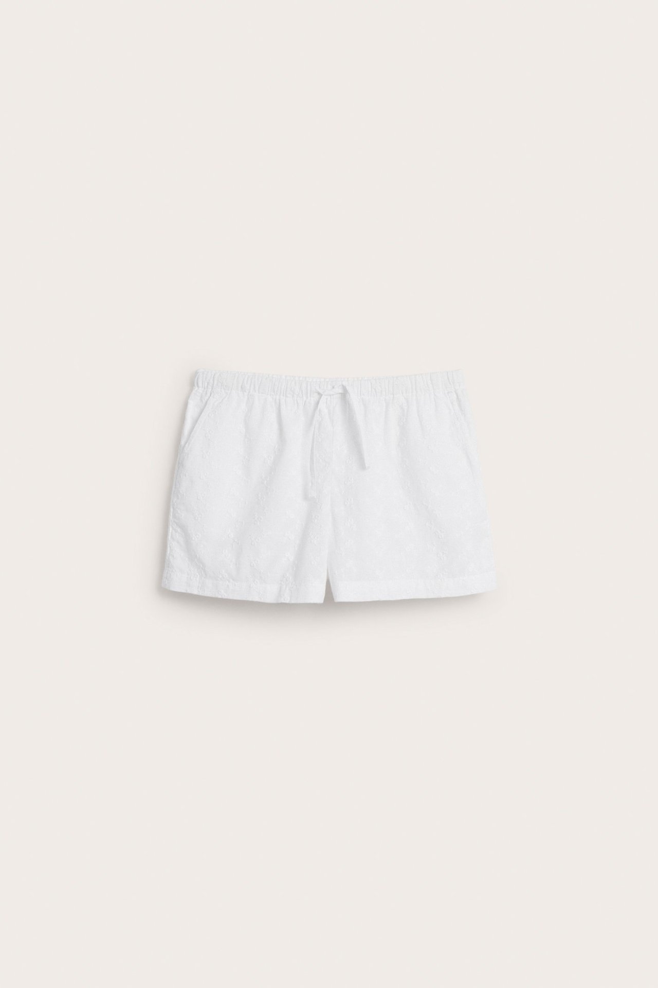 Framsida av vita broderade bomullsshorts med resår och dragsko i midjan samt sidfickor.